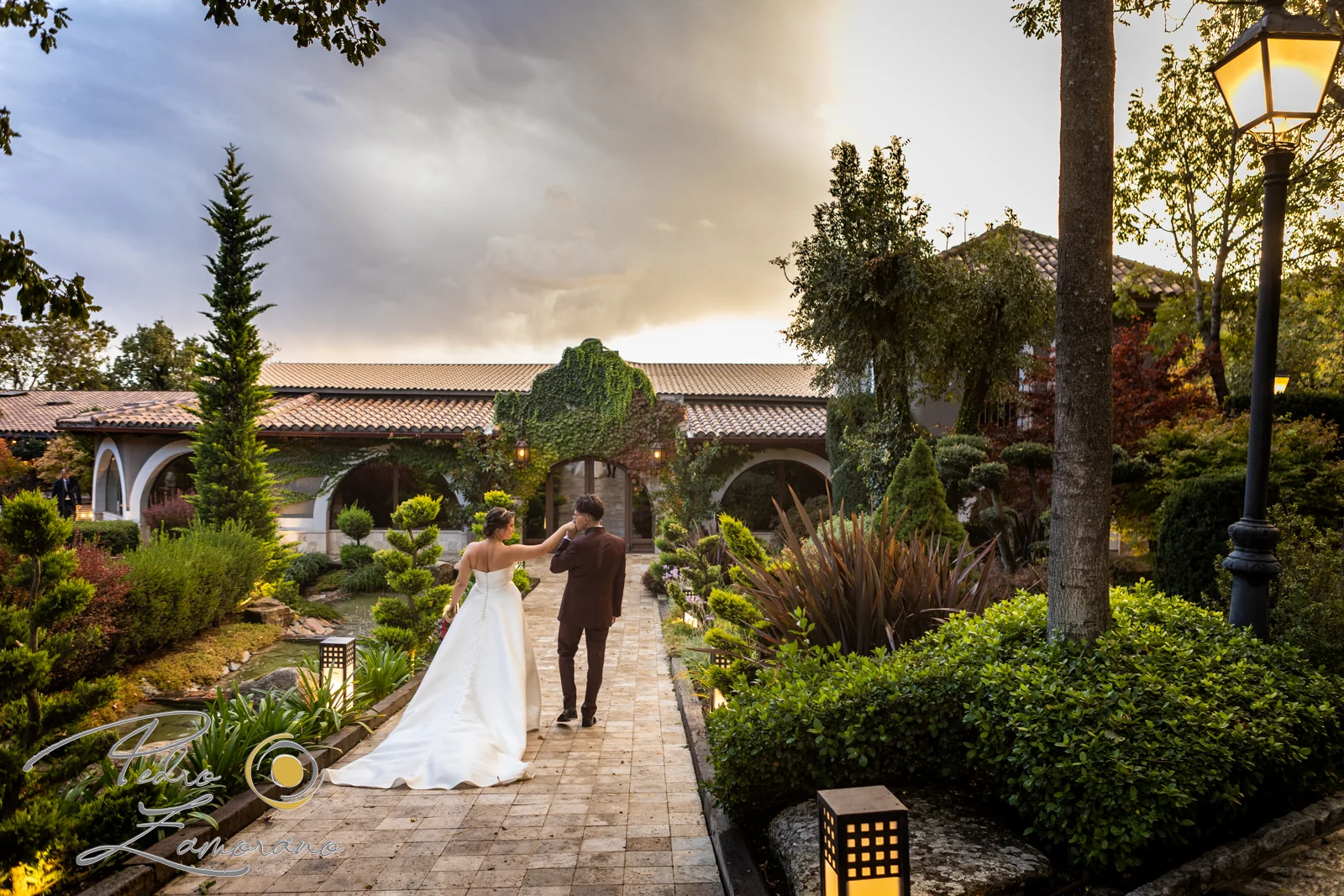 Pareja caminando por los jardines de Hacienda Jacaranda con luz cálida de atardecer.