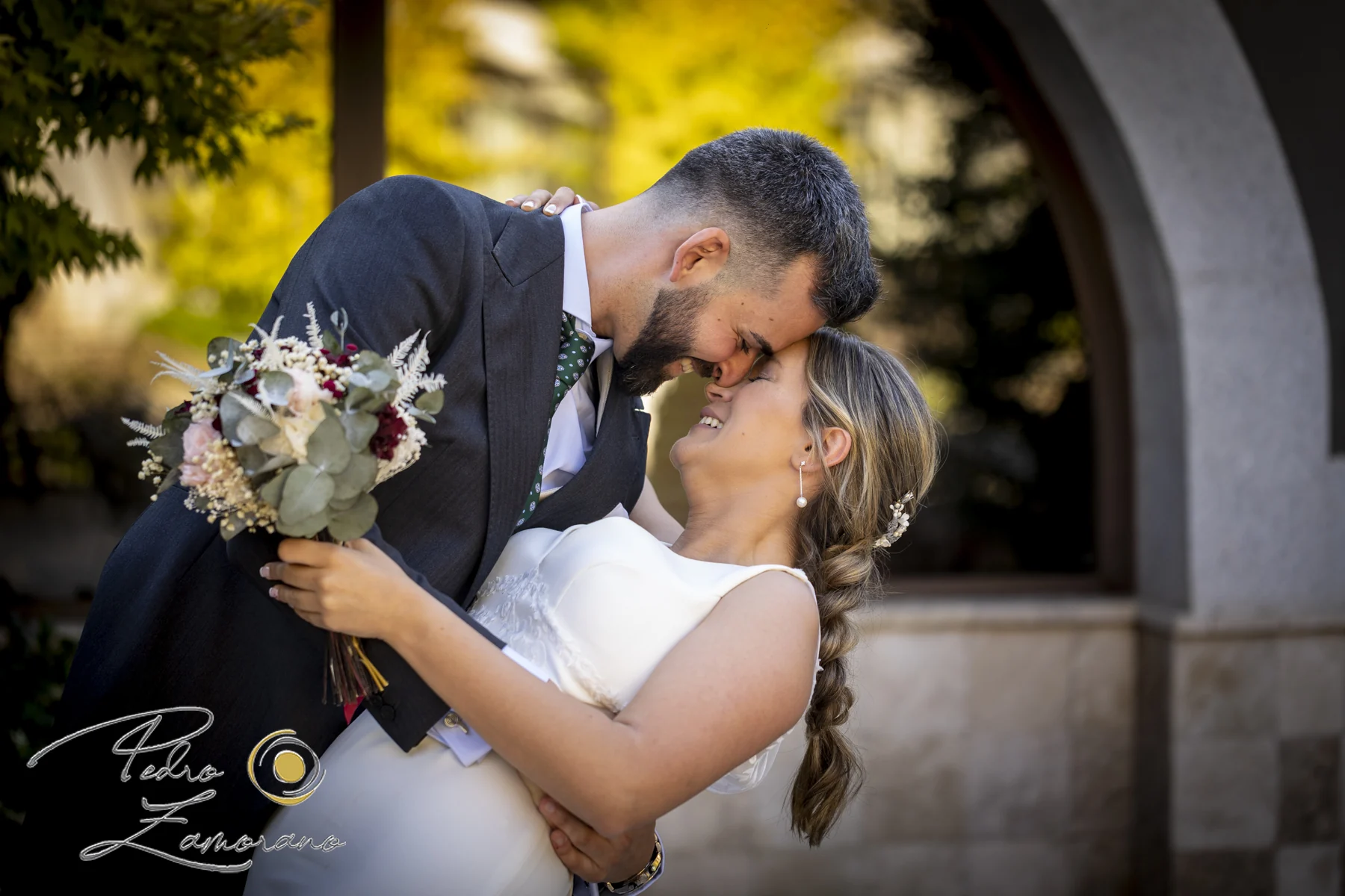 Pareja de novios en un retrato de beso entre jardines de Hacienda Jacaranda.