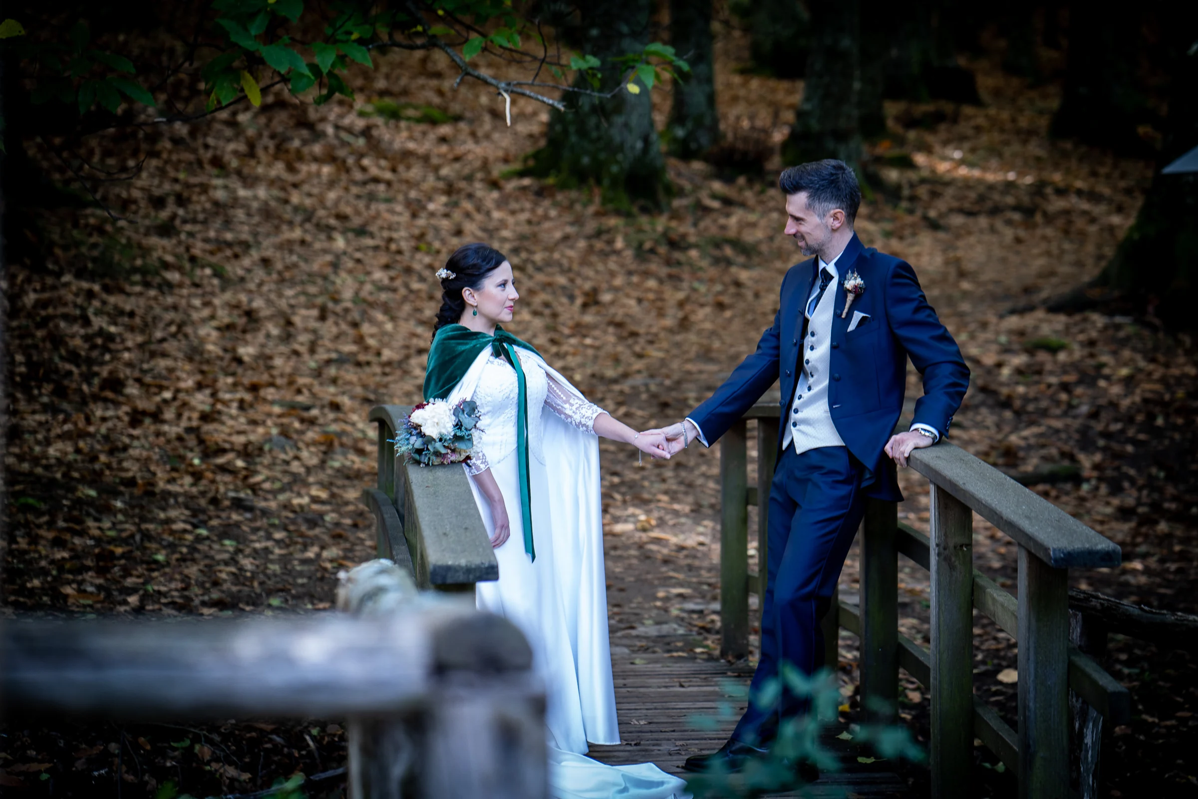 Idoya y Daniel se miran de la mano sobre un puente de madera durante su postboda en el Castañar de El Tiemblo.