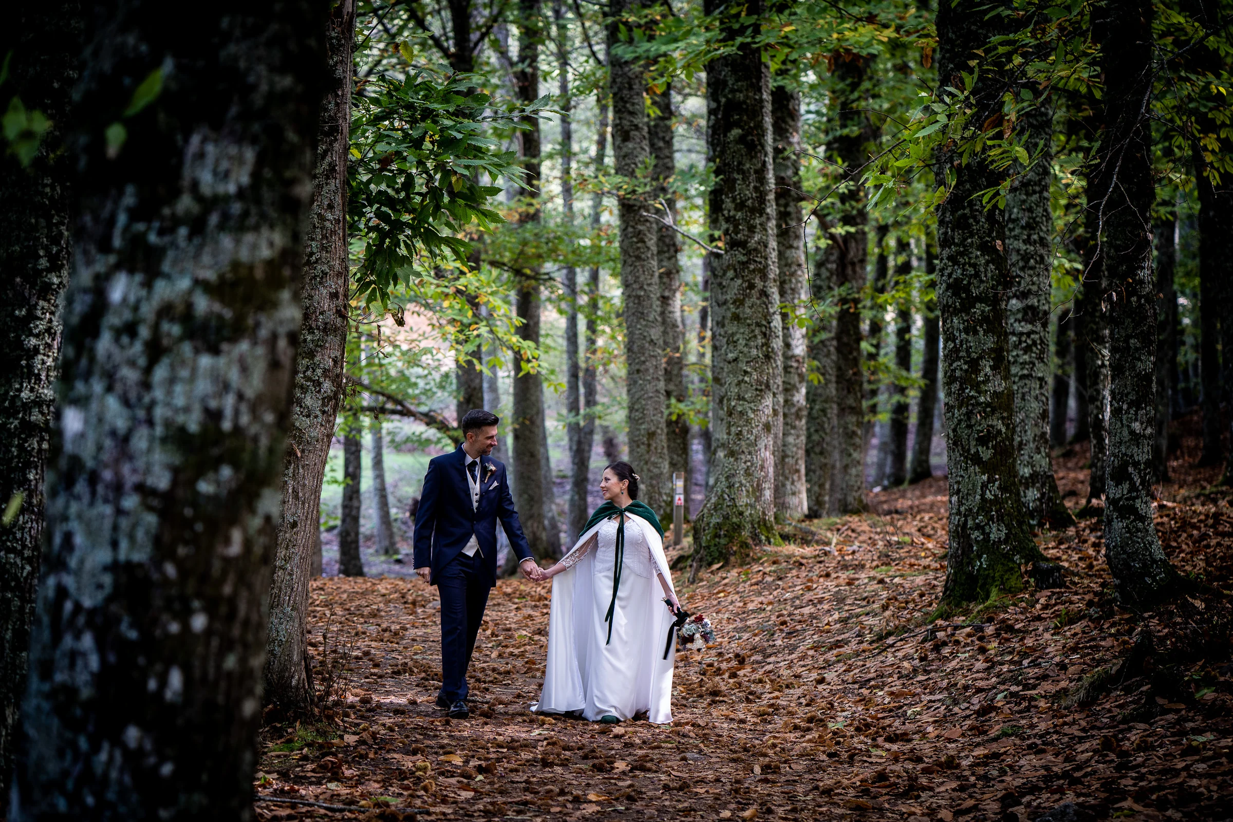 Idoya y Daniel caminan juntos entre los árboles del Castañar de El Tiemblo en una composición enmarcada por el bosque.