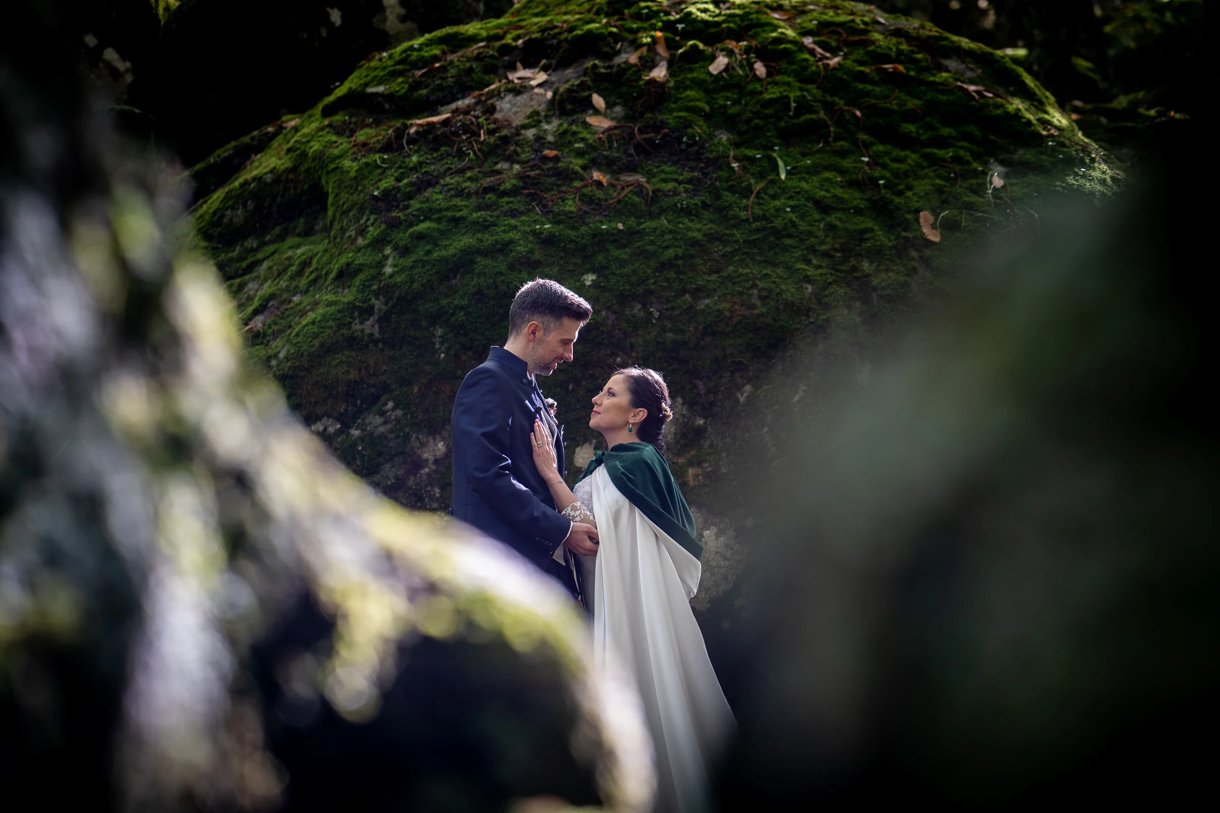 Idoya y Daniel se abrazan entre los árboles del Castañar de El Tiemblo fotografiados a través de la vegetación.