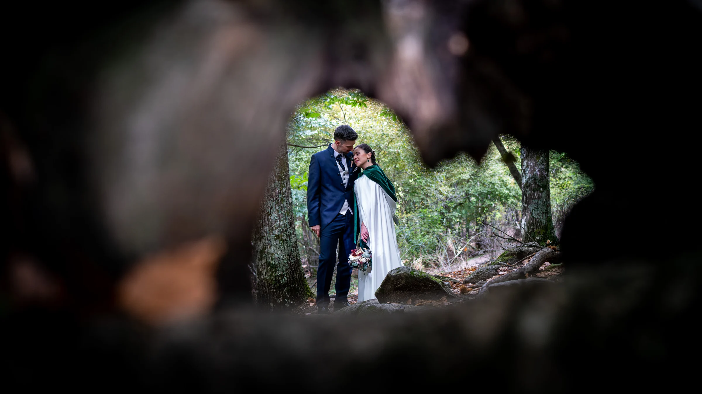 Idoya y Daniel se abrazan en el bosque vistos a través del hueco de un antiguo tronco en el Castañar de El Tiemblo.