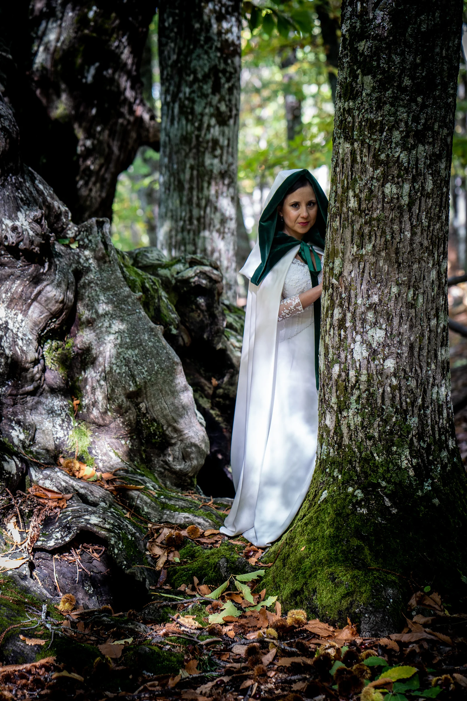 Idoya posa con su capa blanca y verde entre los troncos y raíces del Castañar de El Tiemblo durante su postboda.