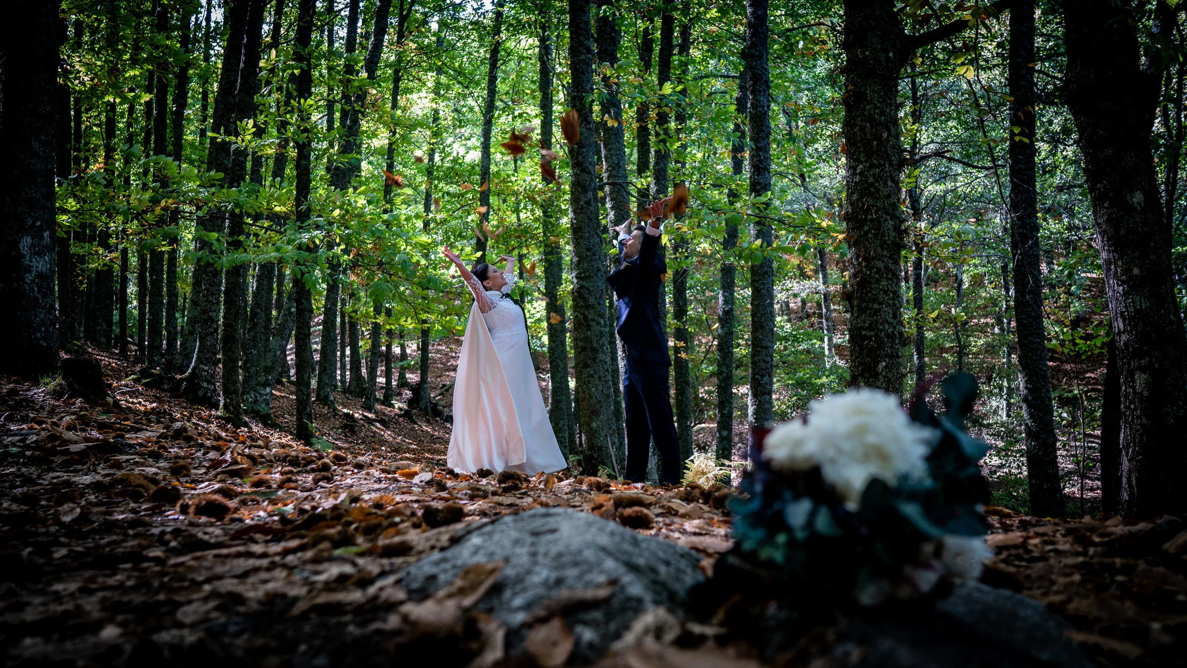Idoya y Daniel lanzan hojas al aire entre los castaños durante un momento divertido de su postboda en El Tiemblo.