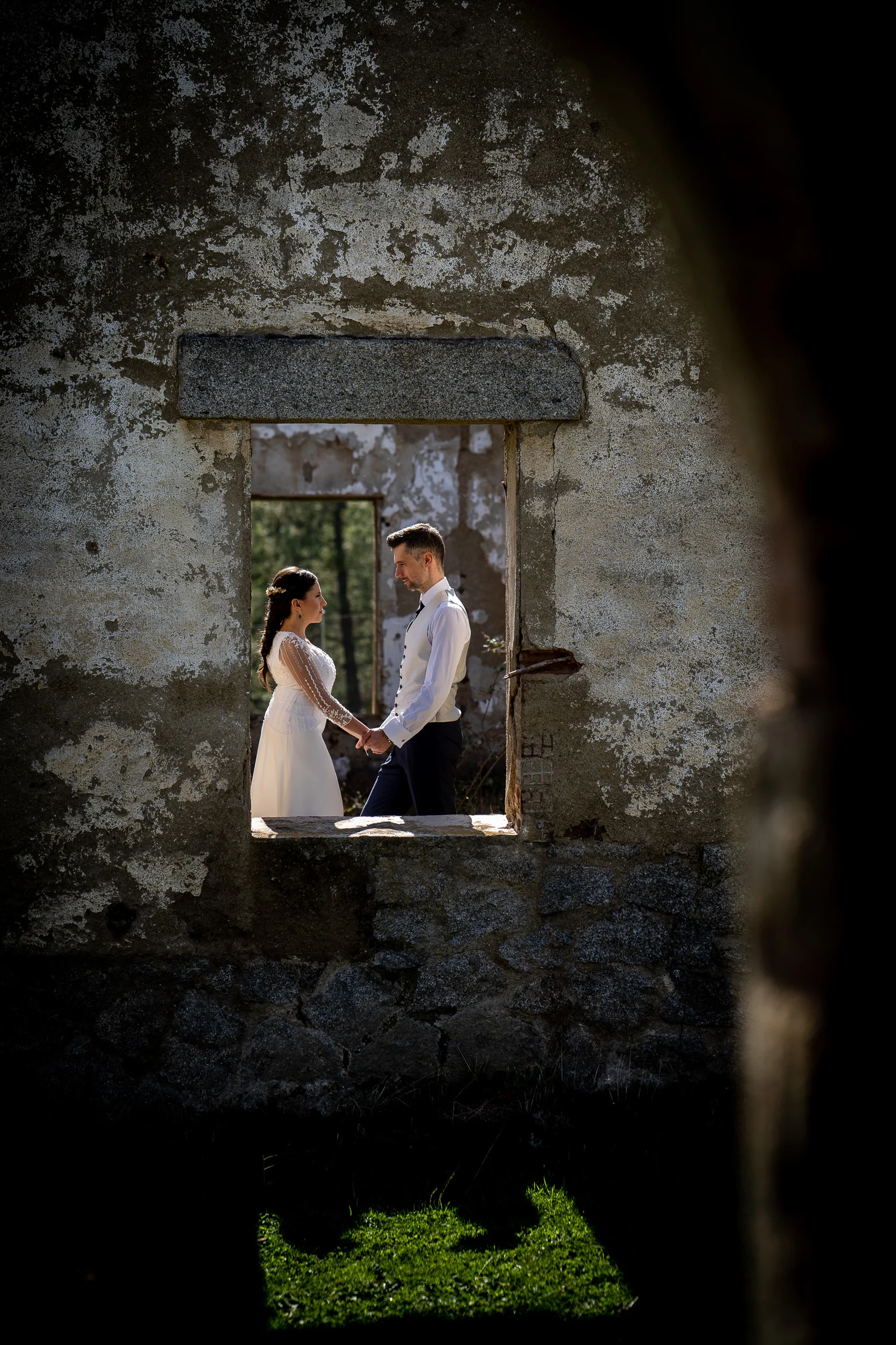 Idoya y Daniel se toman de las manos dentro del marco de una ventana de piedra en un edificio en ruinas de El Tiemblo.