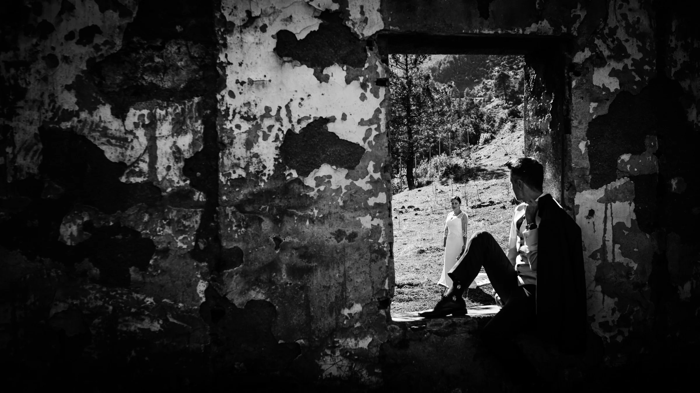 Daniel observa a Idoya desde el interior oscuro de un edificio en ruinas en una fotografía en blanco y negro de su postboda en El Tiemblo.