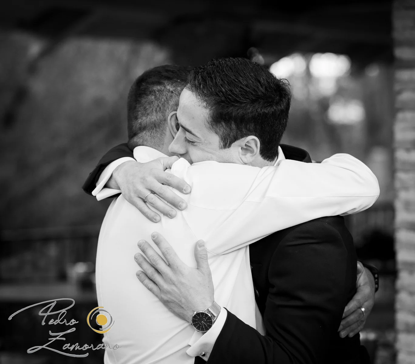 Abrazo emotivo entre dos invitados durante una boda en Jardín El Botero fotografiado en blanco y negro.