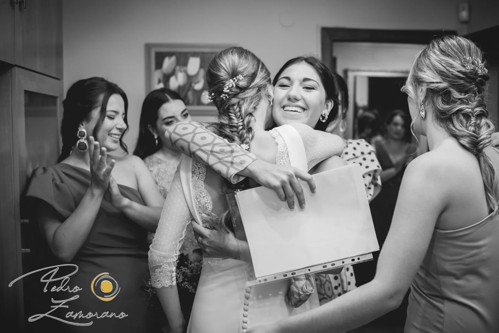 Novia abrazando sonriente a una amiga rodeada de invitadas antes de la celebración en Jardín El Botero.