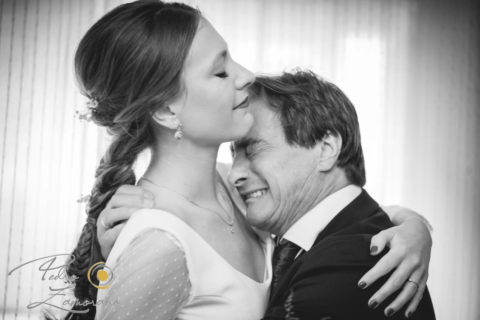 Novia abrazando con emoción a un familiar antes de la ceremonia en una fotografía en blanco y negro.
