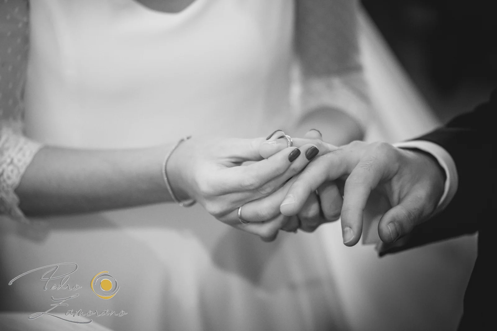 Primer plano de las manos de los novios durante el intercambio de alianzas en una ceremonia de boda.