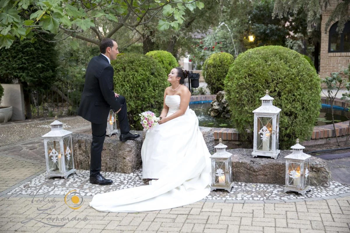 Novios conversando junto a una fuente decorada con faroles en uno de los jardines de Jardín El Botero.