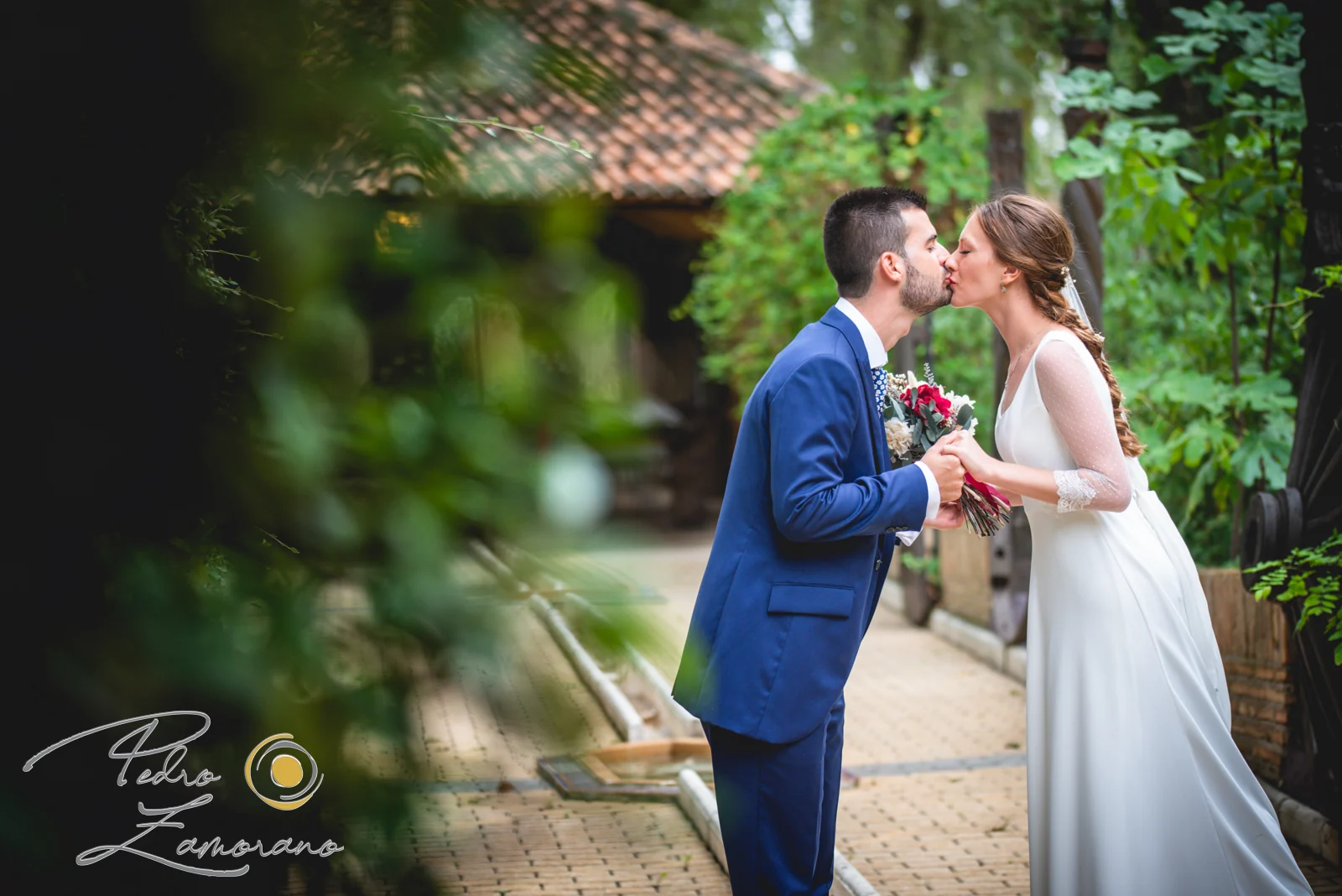 Novios besándose en un paseo rodeado de vegetación dentro de Jardín El Botero.