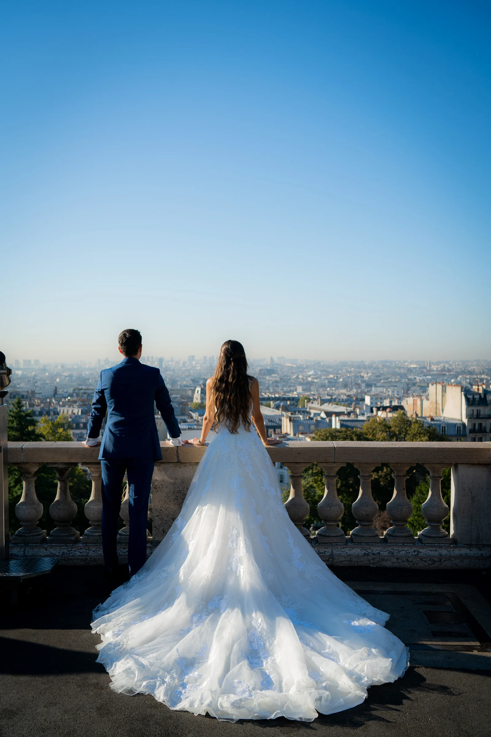 José Luis y Lara contemplan París desde un mirador de Montmartre, vistos de espaldas junto al vestido de Lara.
