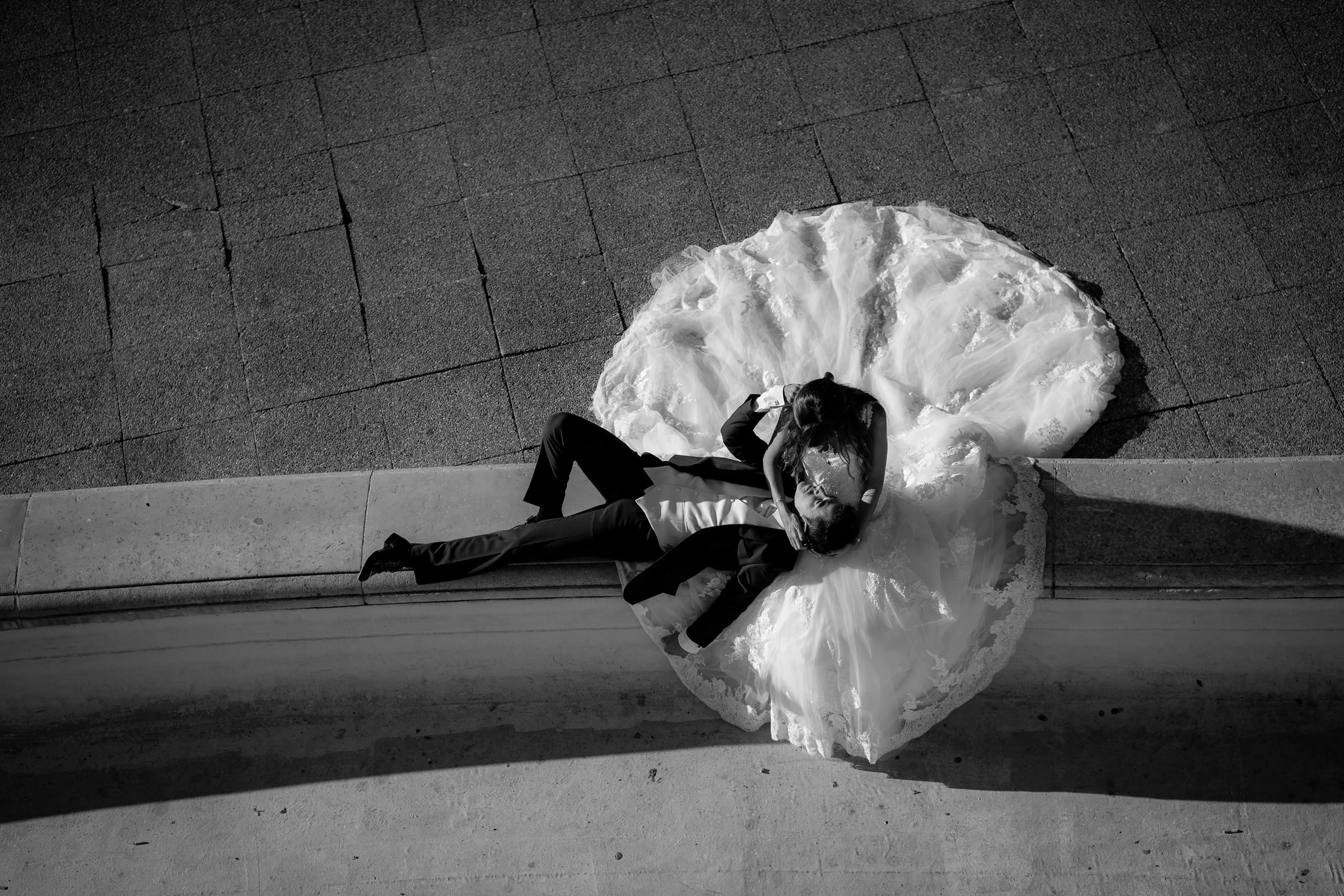 Vista cenital en blanco y negro de José Luis y Lara rodeados por el vestido de la novia durante su postboda en París.