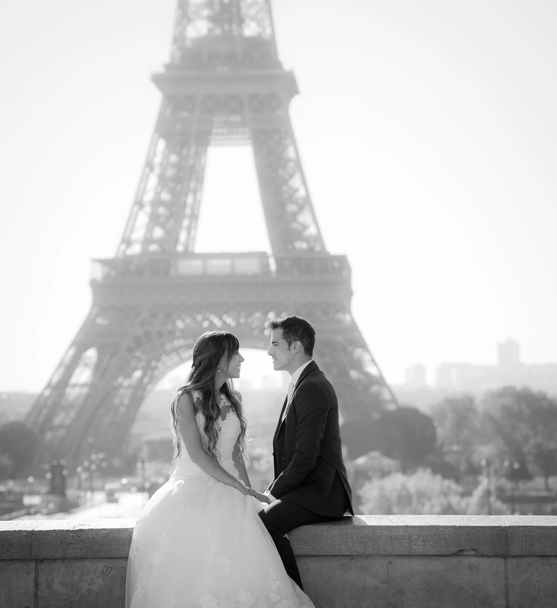José Luis y Lara sentados frente a la Torre Eiffel en un retrato en blanco y negro.