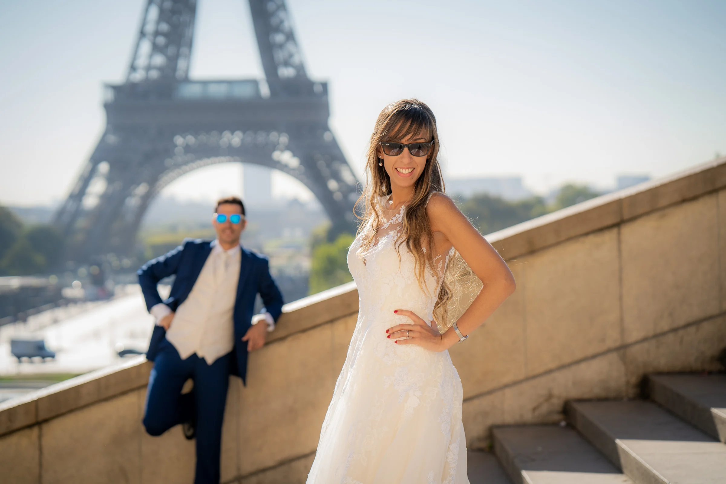 Lara sonríe con gafas de sol frente a la Torre Eiffel mientras José Luis queda desenfocado al fondo.