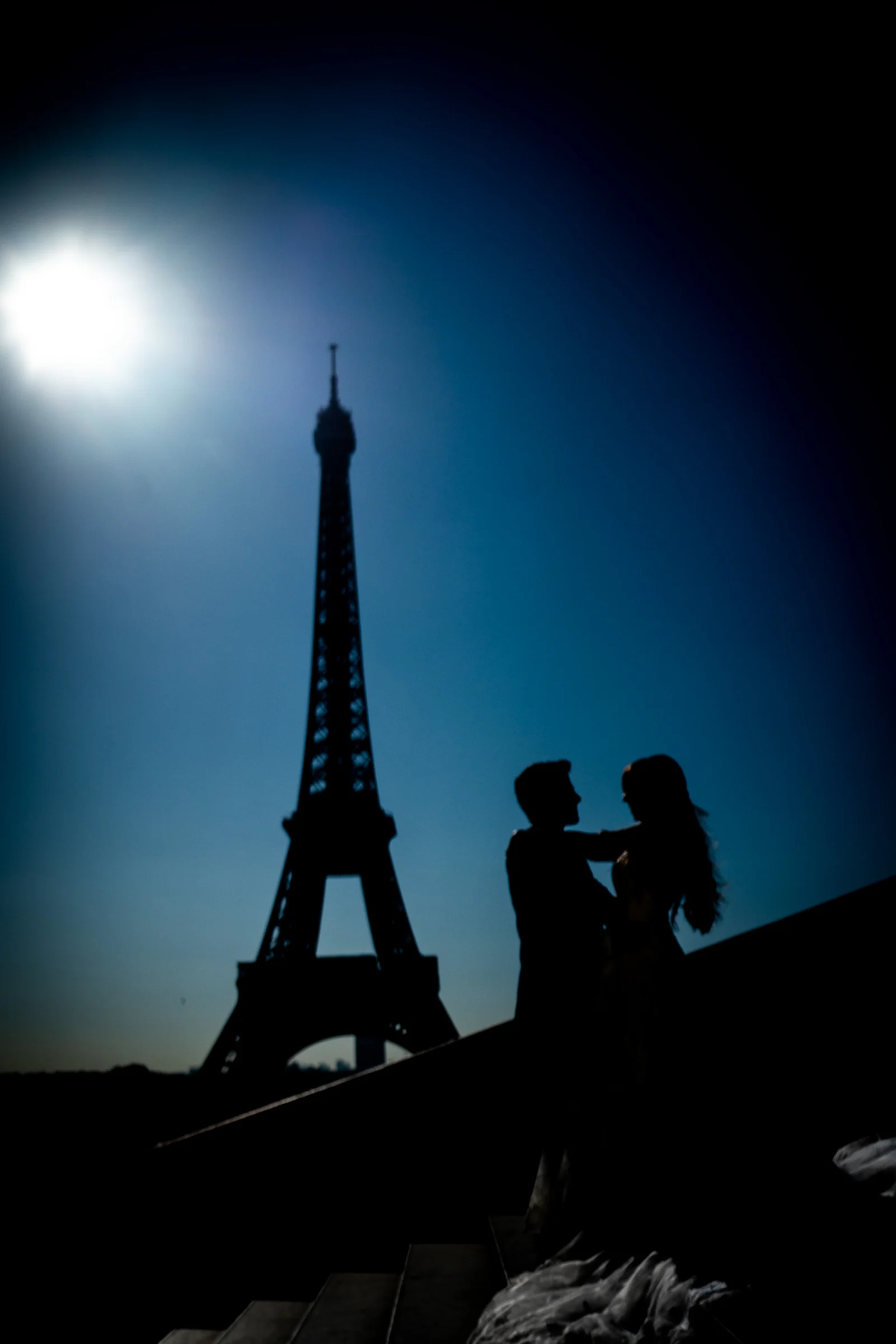 Silueta de José Luis y Lara junto a la Torre Eiffel y el sol alto durante su postboda en París.
