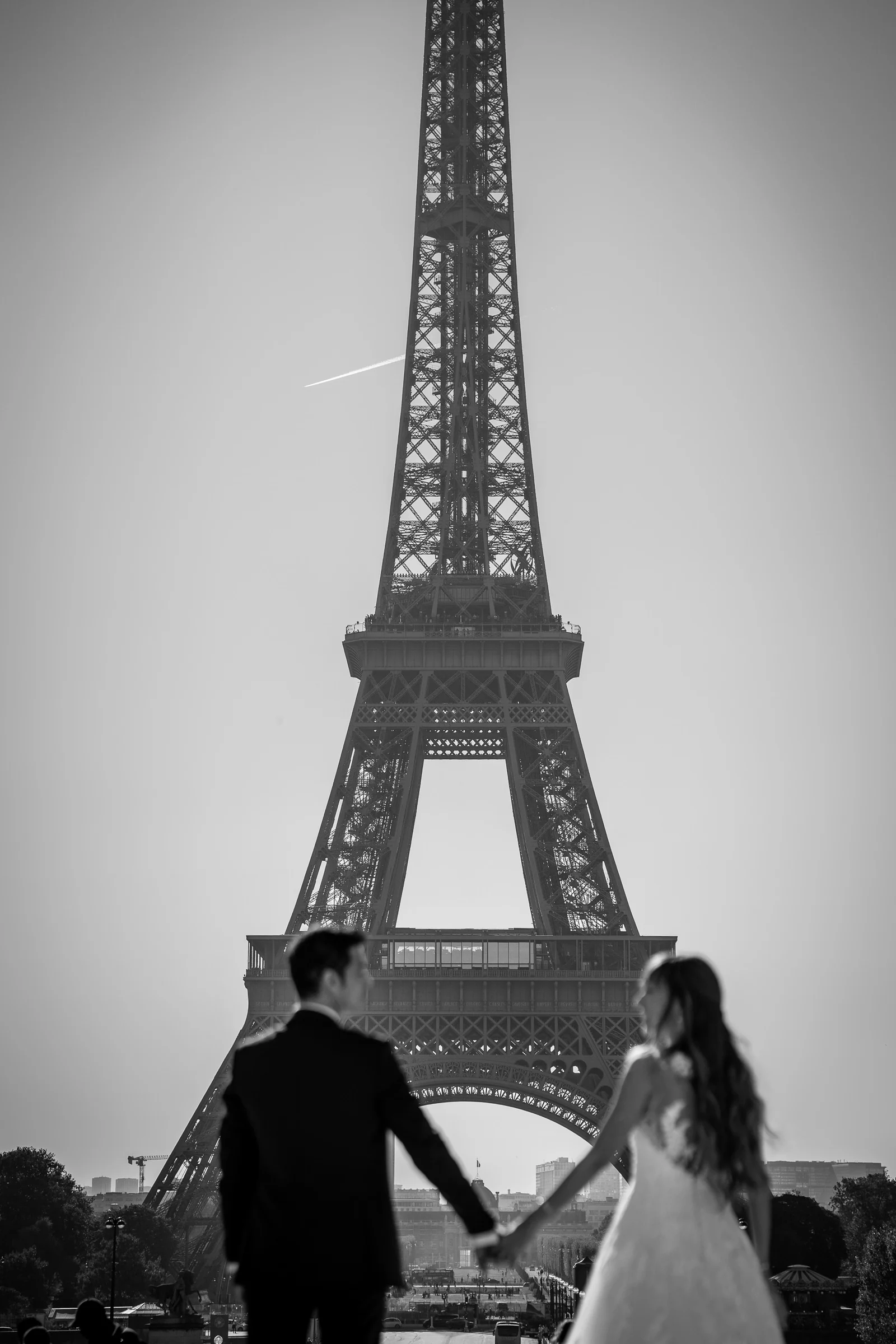 José Luis y Lara se dan la mano ante la Torre Eiffel en una fotografía vertical en blanco y negro.