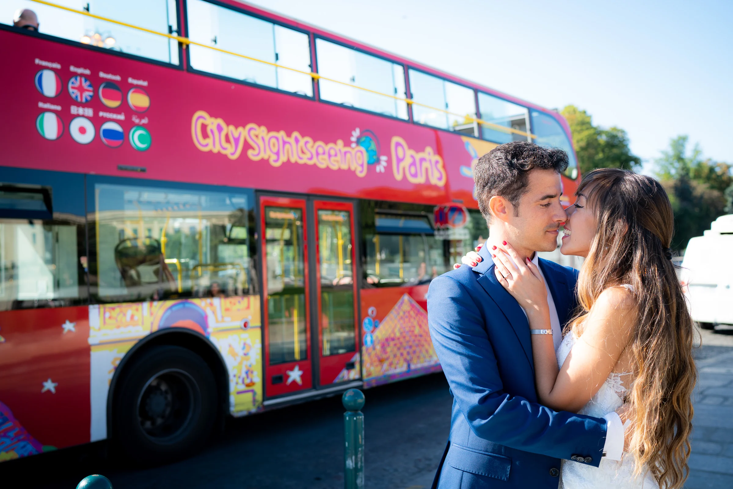 José Luis y Lara se abrazan junto a un autobús turístico rojo durante su postboda por París.