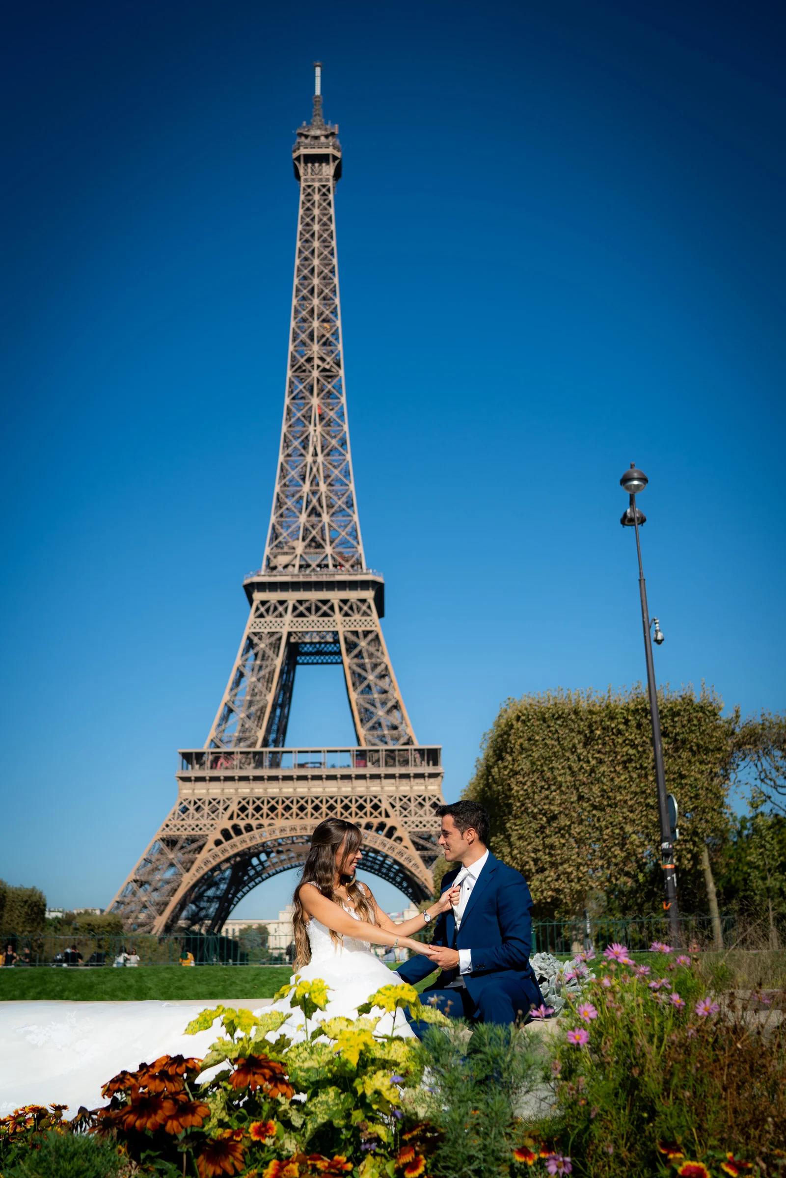 José Luis y Lara sentados entre flores con la Torre Eiffel completa al fondo.