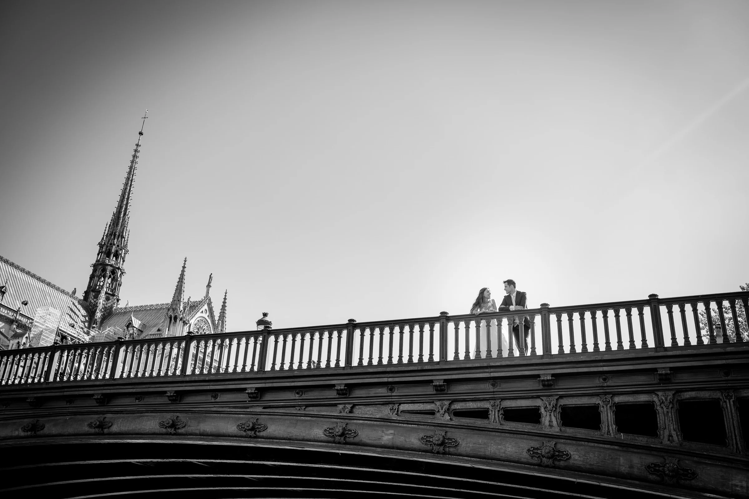José Luis y Lara en un puente junto a Notre-Dame en una composición panorámica en blanco y negro.