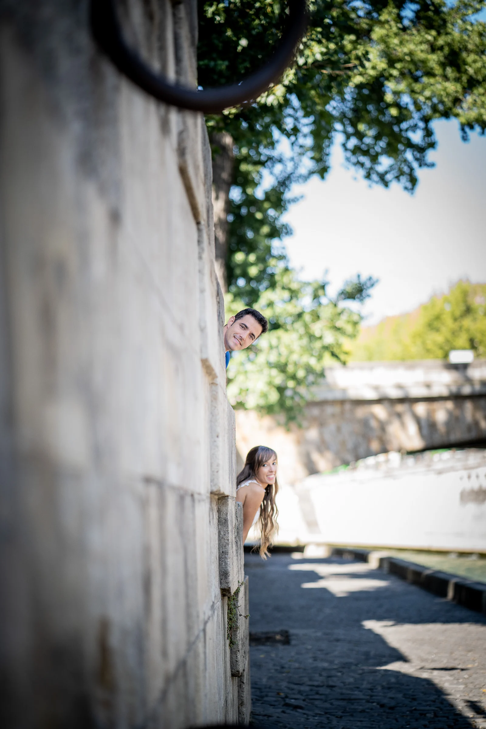 José Luis y Lara asoman sonrientes desde un muro junto al Sena durante su postboda en París.