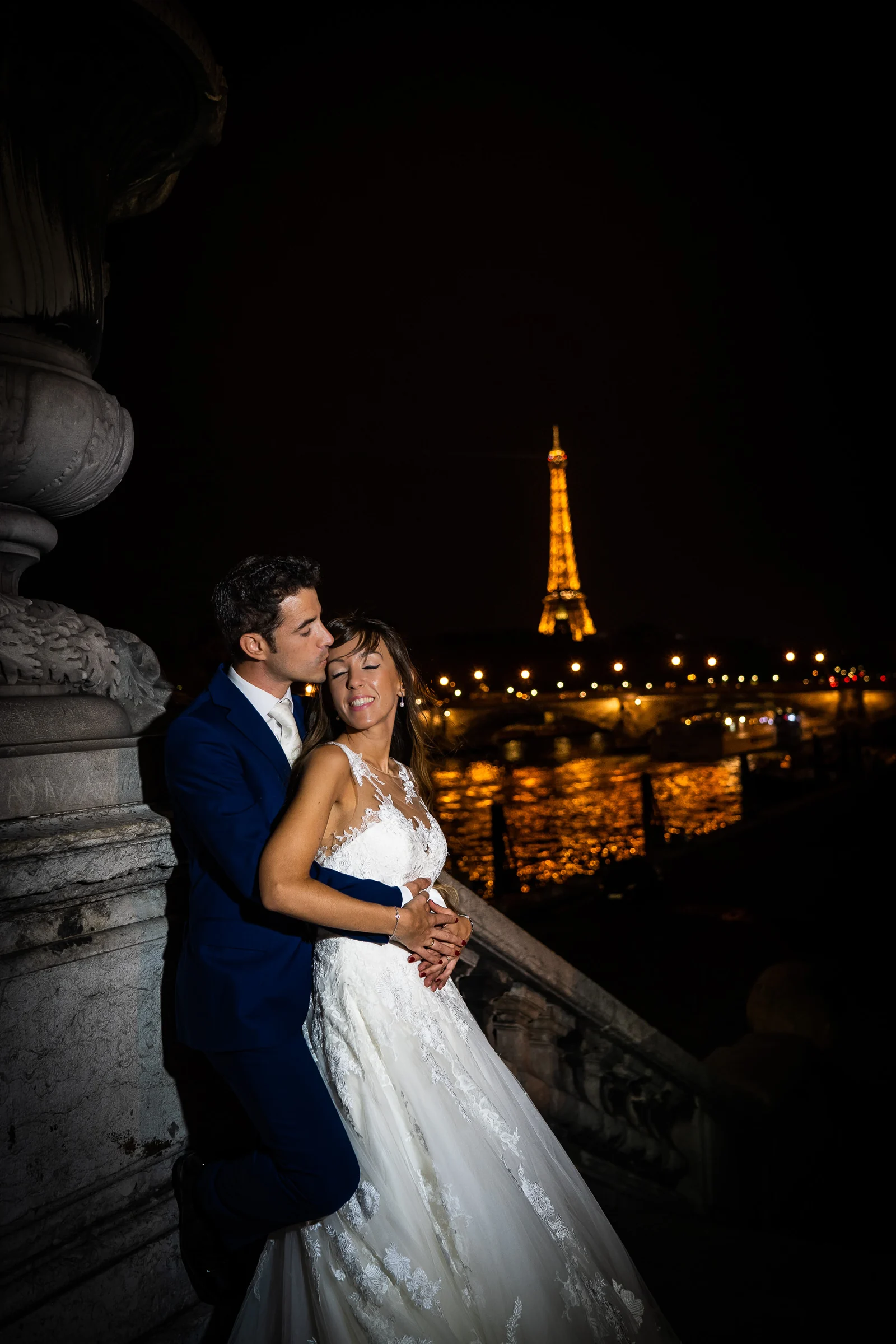José Luis besa a Lara junto al Sena de noche con la Torre Eiffel iluminada al fondo.