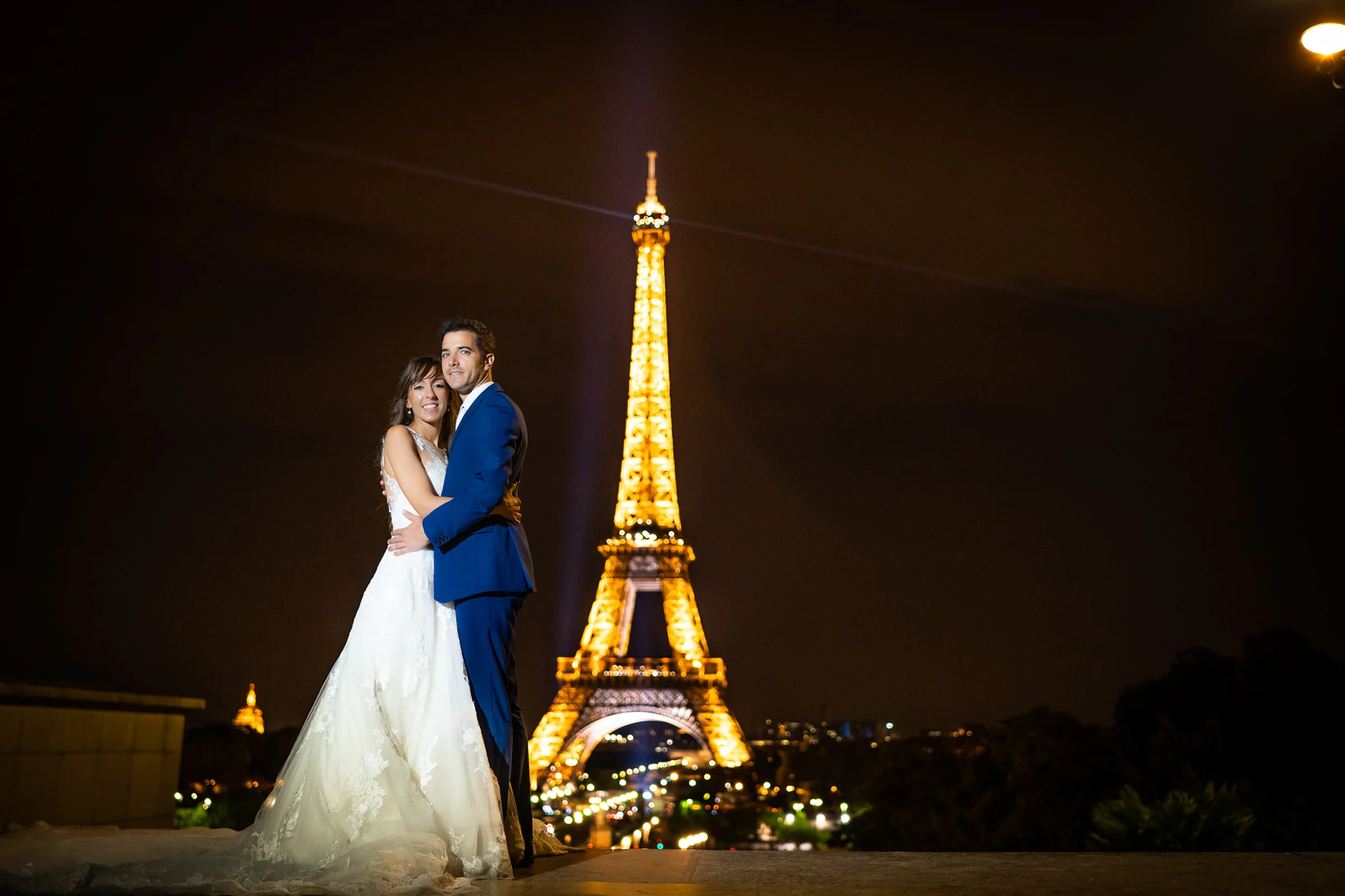 José Luis y Lara abrazados con la Torre Eiffel iluminada detrás al final de su postboda en París.