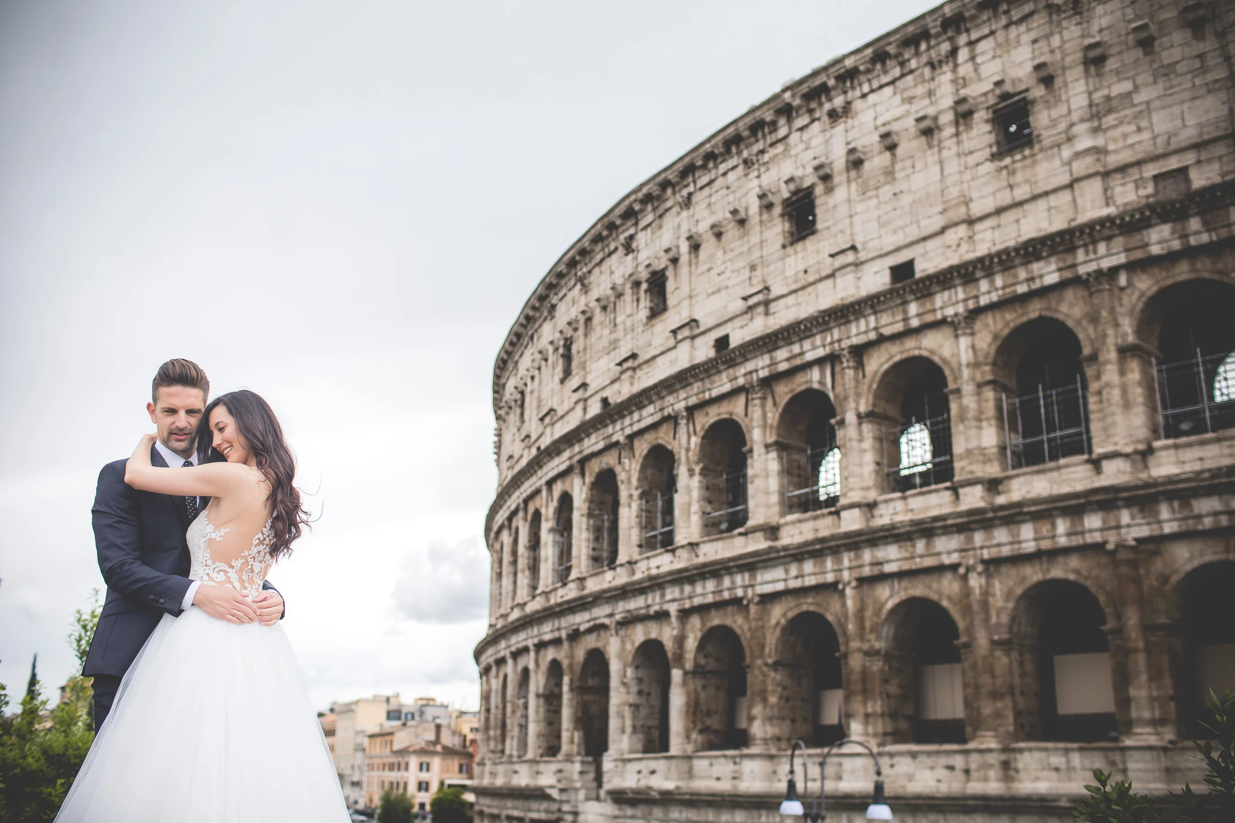Retrato de la pareja junto a la fachada del Coliseo durante una sesión postboda en Coliseo de Roma.