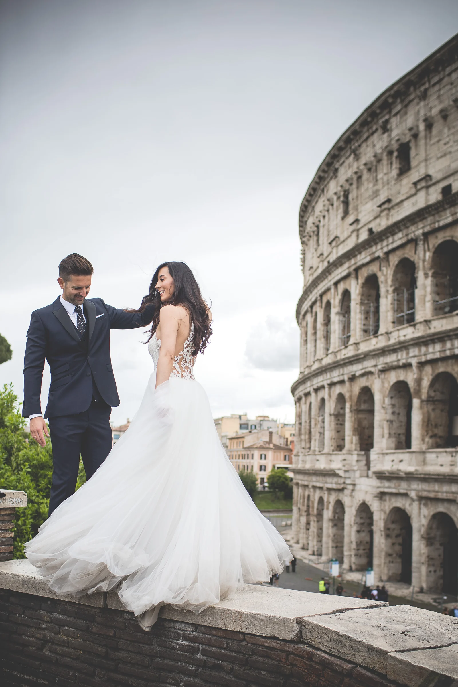 Los novios caminan de la mano por un camino junto al Coliseo durante una sesión postboda en Coliseo de Roma.