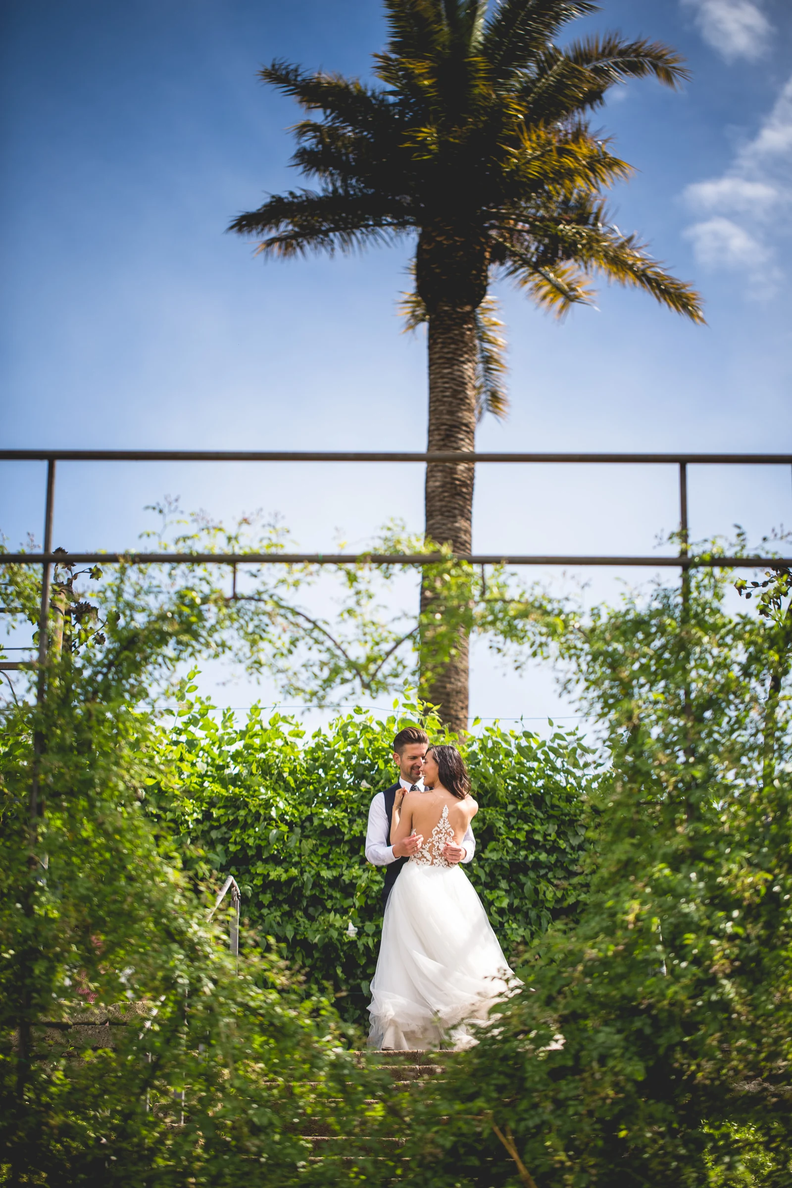 La novia posa sola bajo una pérgola de jardín con una palmera al fondo durante una sesión postboda en Jardines y miradores de Roma.