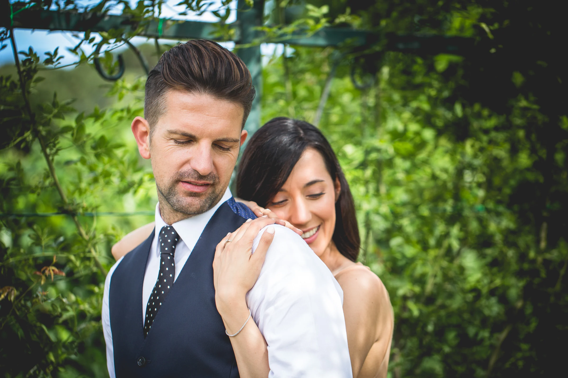 Retrato cercano de la pareja abrazada entre vegetación verde durante una sesión postboda en Jardines y miradores de Roma.