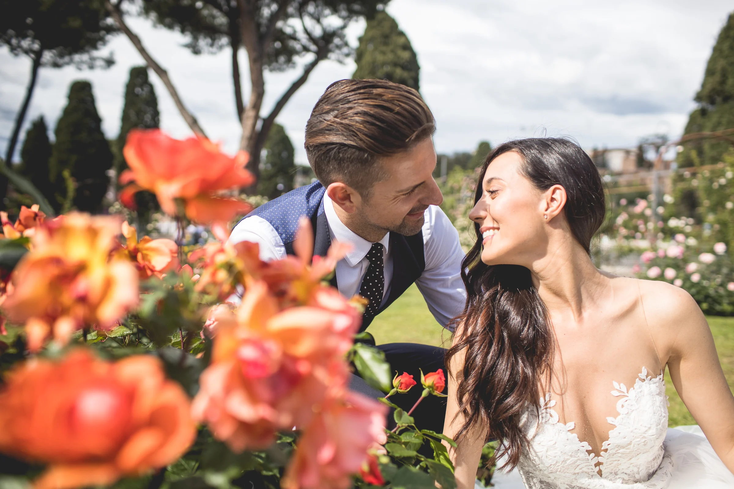 La pareja sonríe entre rosas naranjas en un primer plano luminoso durante una sesión postboda en Jardines y miradores de Roma.
