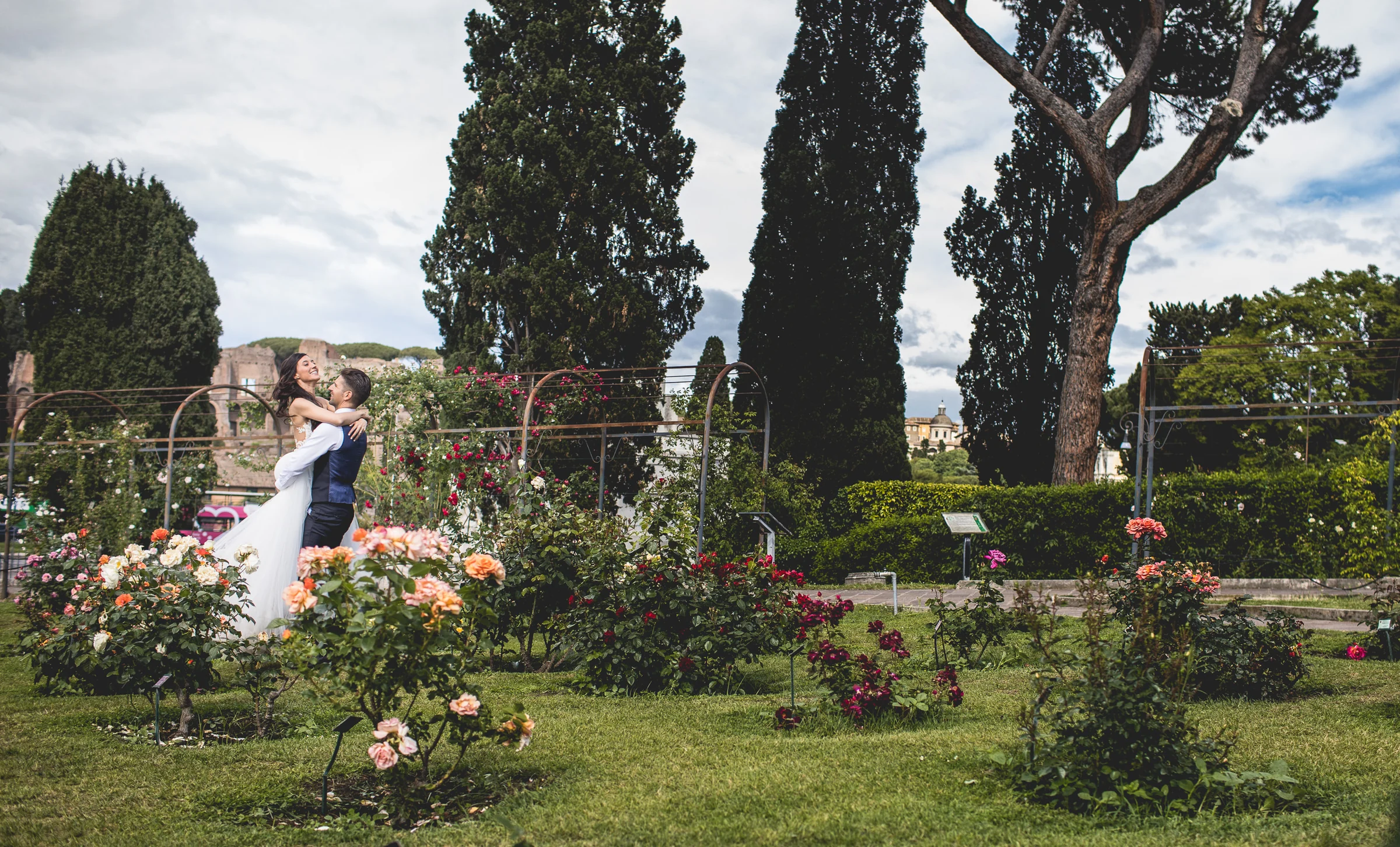 Vista amplia de los novios en un jardín de rosas romano durante una sesión postboda en Jardines y miradores de Roma.