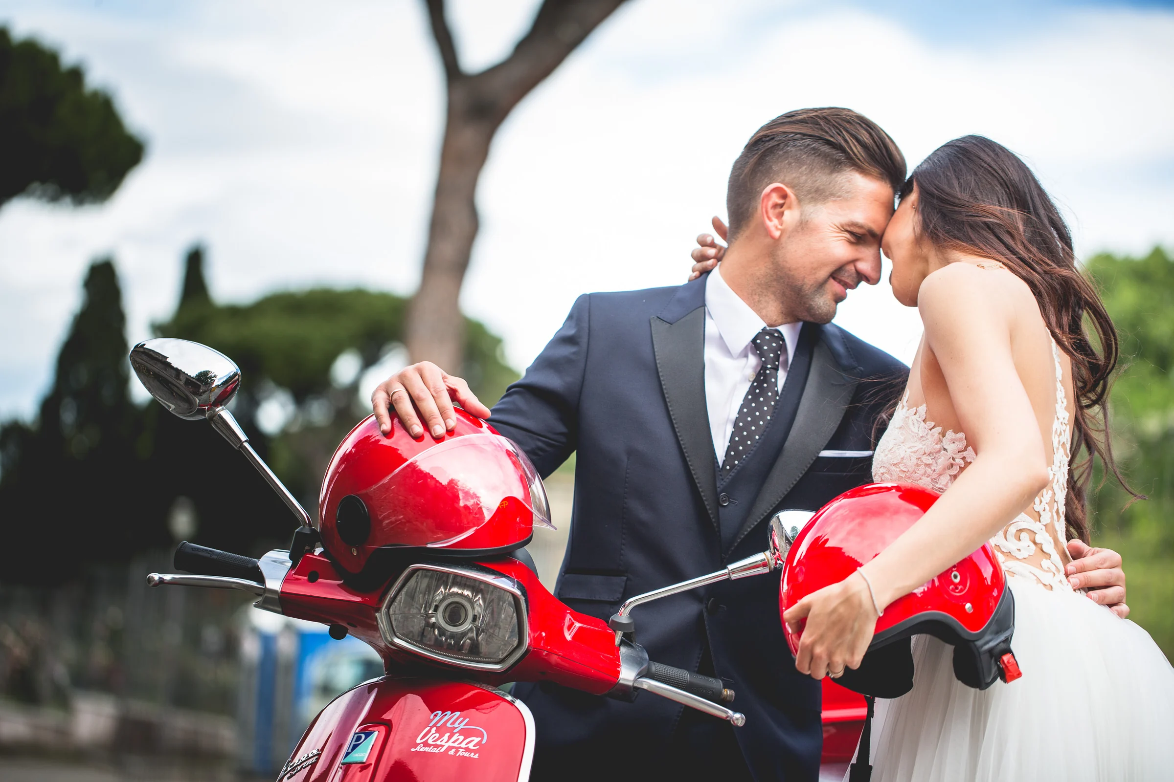 Retrato cercano de la pareja apoyada en una Vespa roja durante una sesión postboda en Calles de Roma con Vespa.