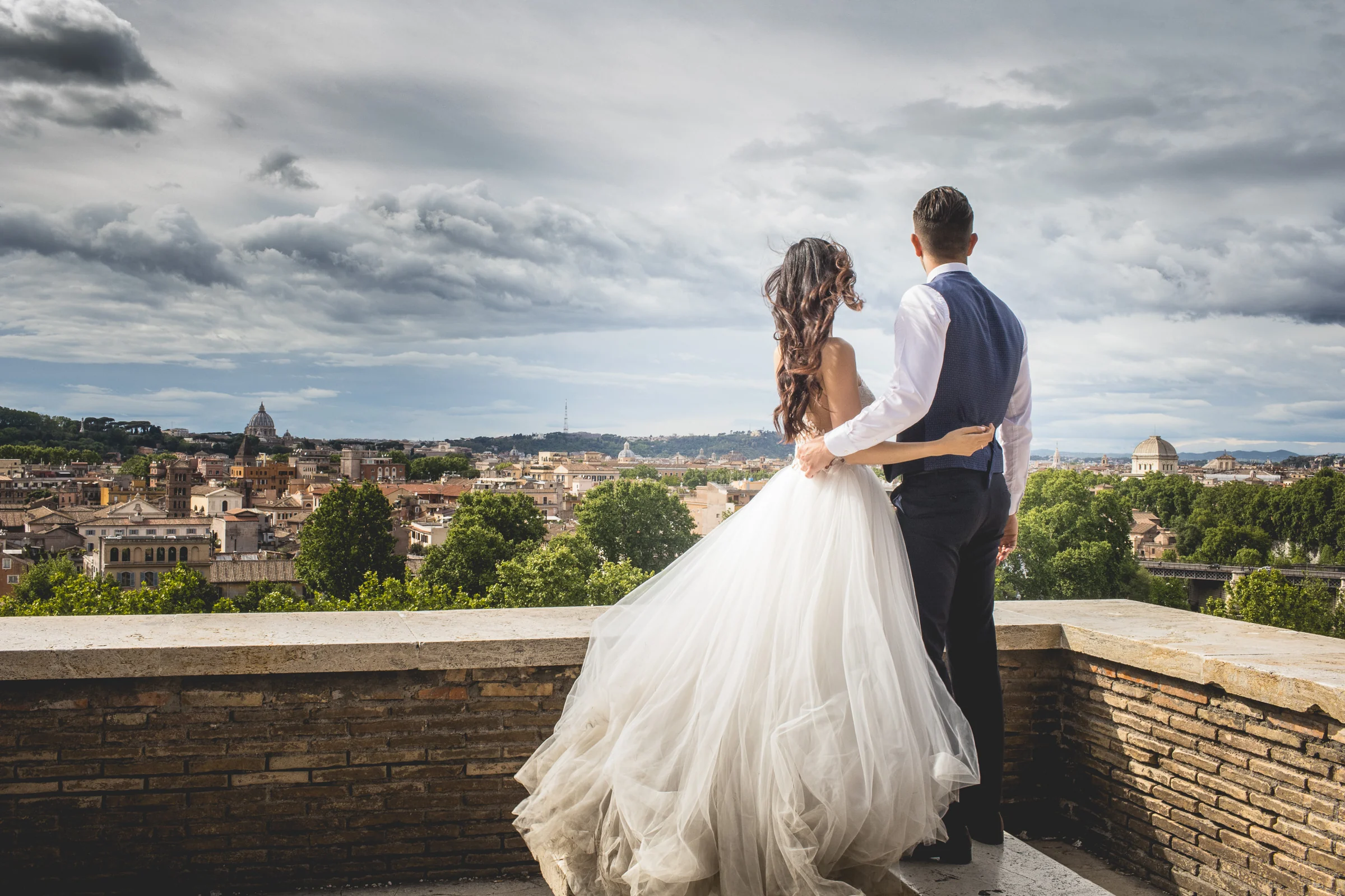 Los novios abrazados contemplan una vista panorámica de Roma durante una sesión postboda en Miradores y jardines de Roma.