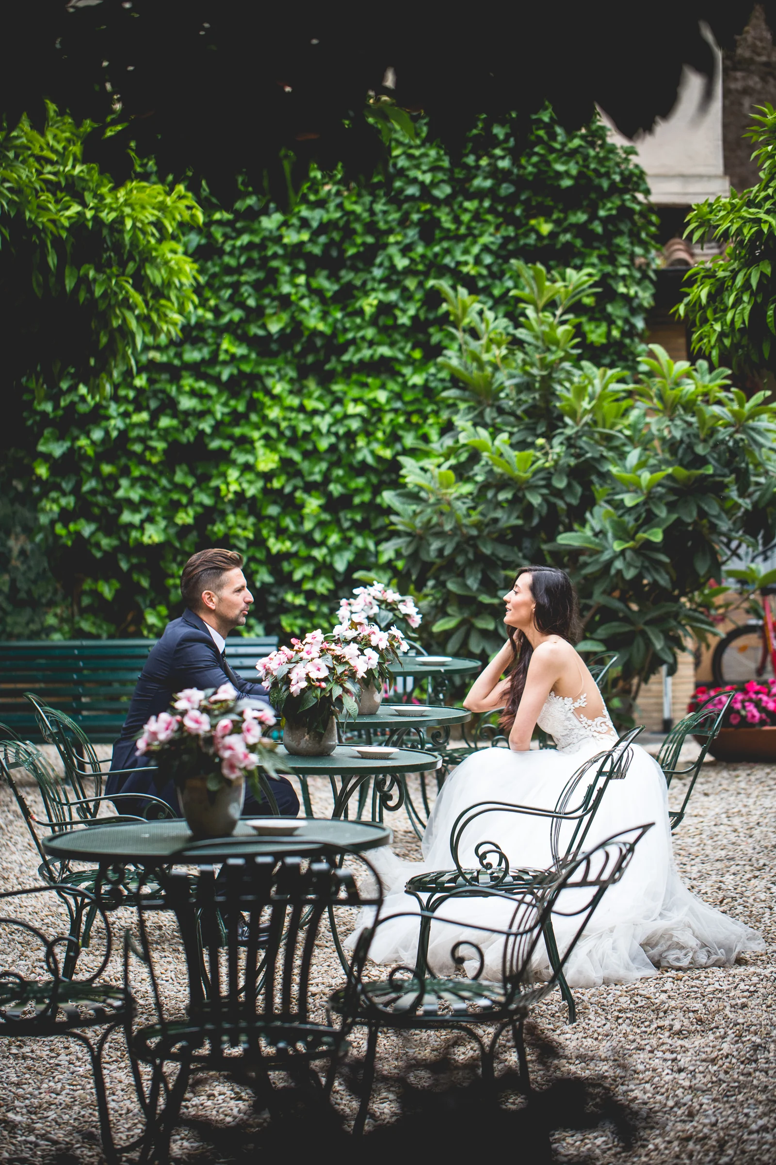 Los novios sentados en una terraza exterior rodeada de vegetación durante una sesión postboda en Miradores y centro histórico de Roma.