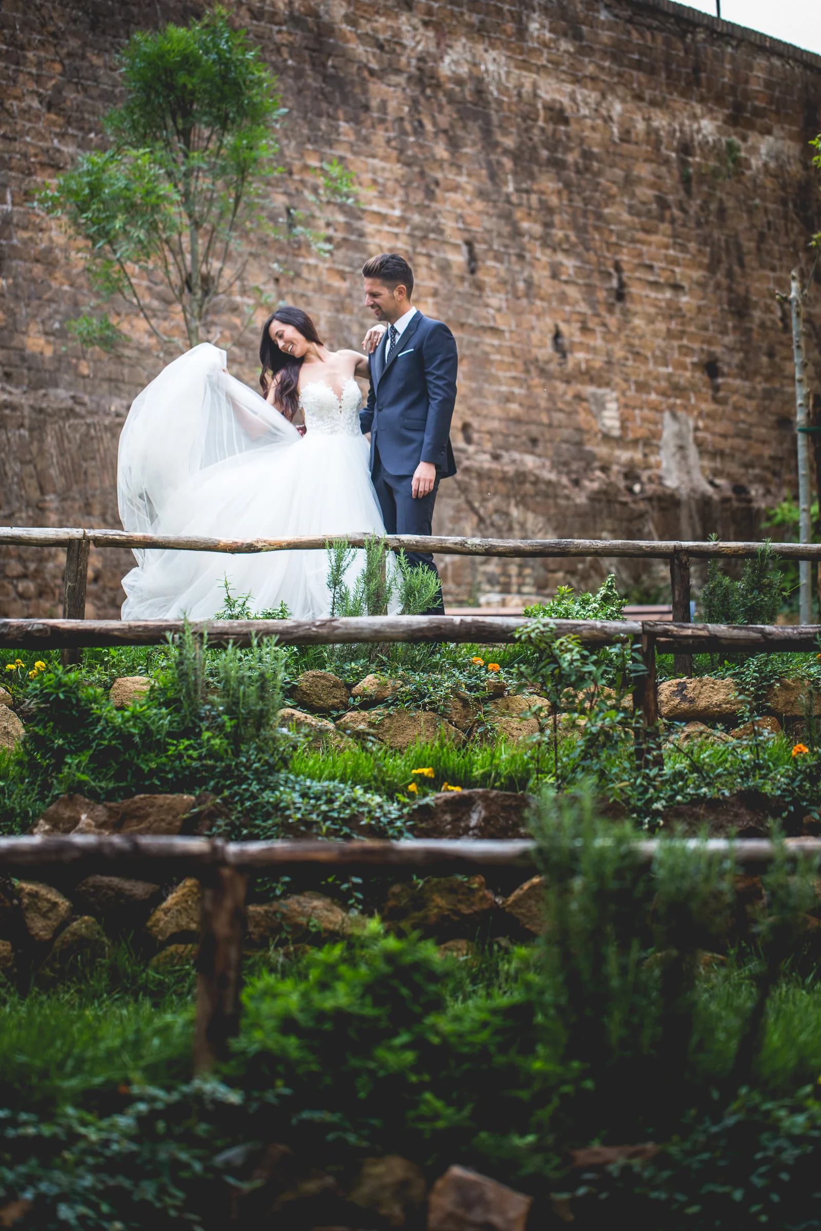 Los novios aparecen en una escalinata estrecha rodeada de muros antiguos durante una sesión postboda en Miradores y centro histórico de Roma.
