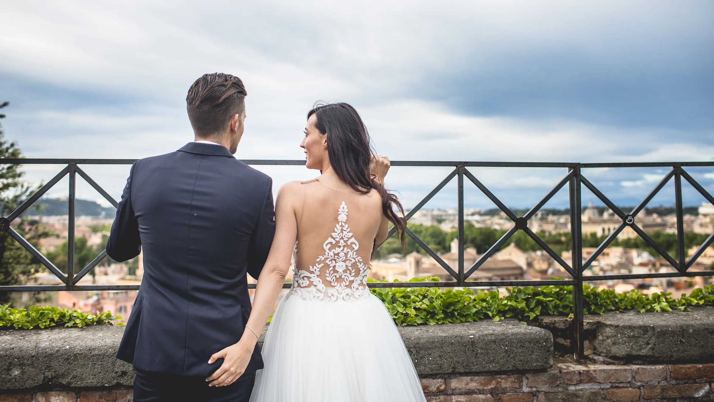 La pareja contempla Roma desde un mirador con barandilla durante una sesión postboda en Miradores y centro histórico de Roma.