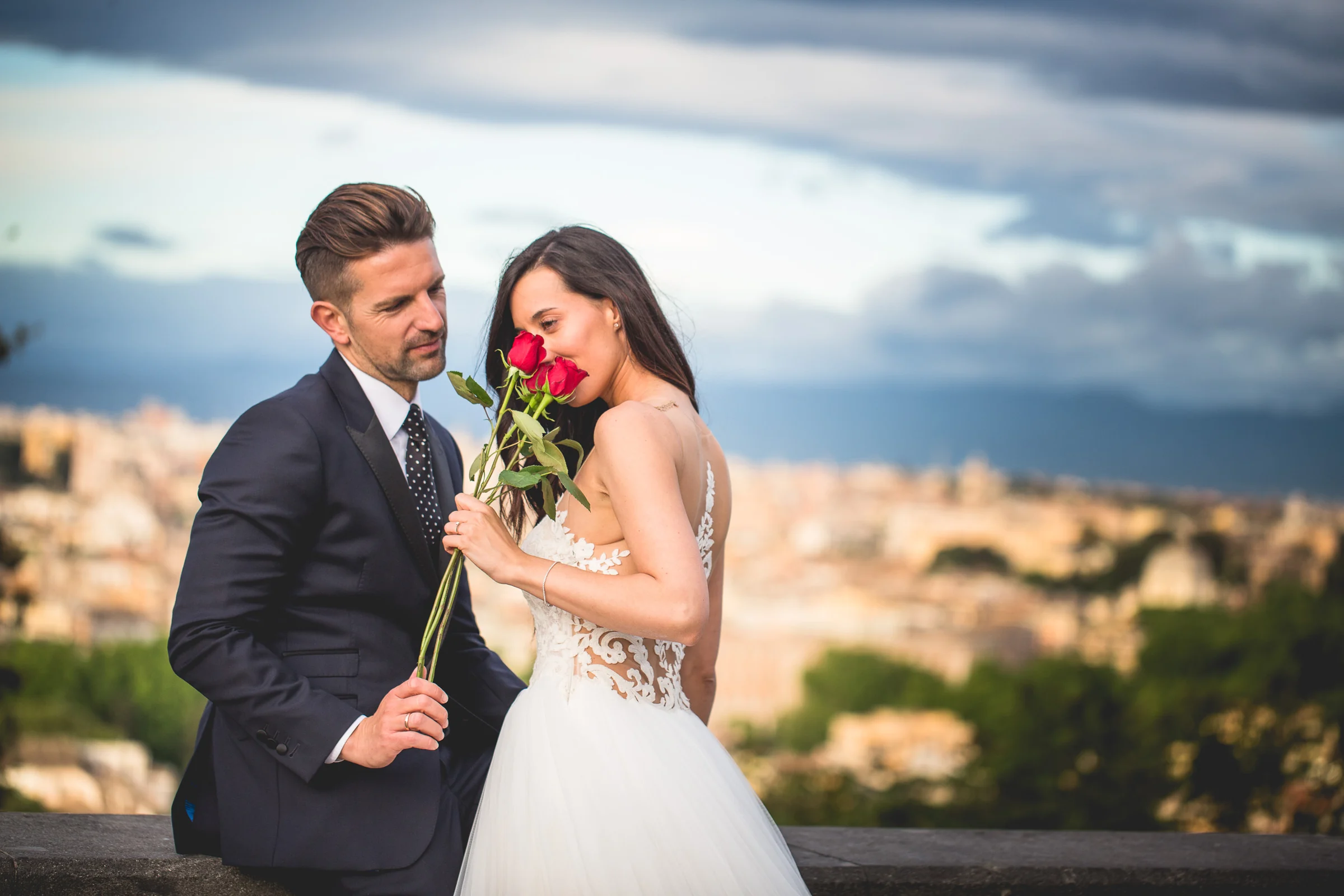 La pareja posa con una rosa roja en un mirador sobre Roma durante una sesión postboda en Miradores y centro histórico de Roma.