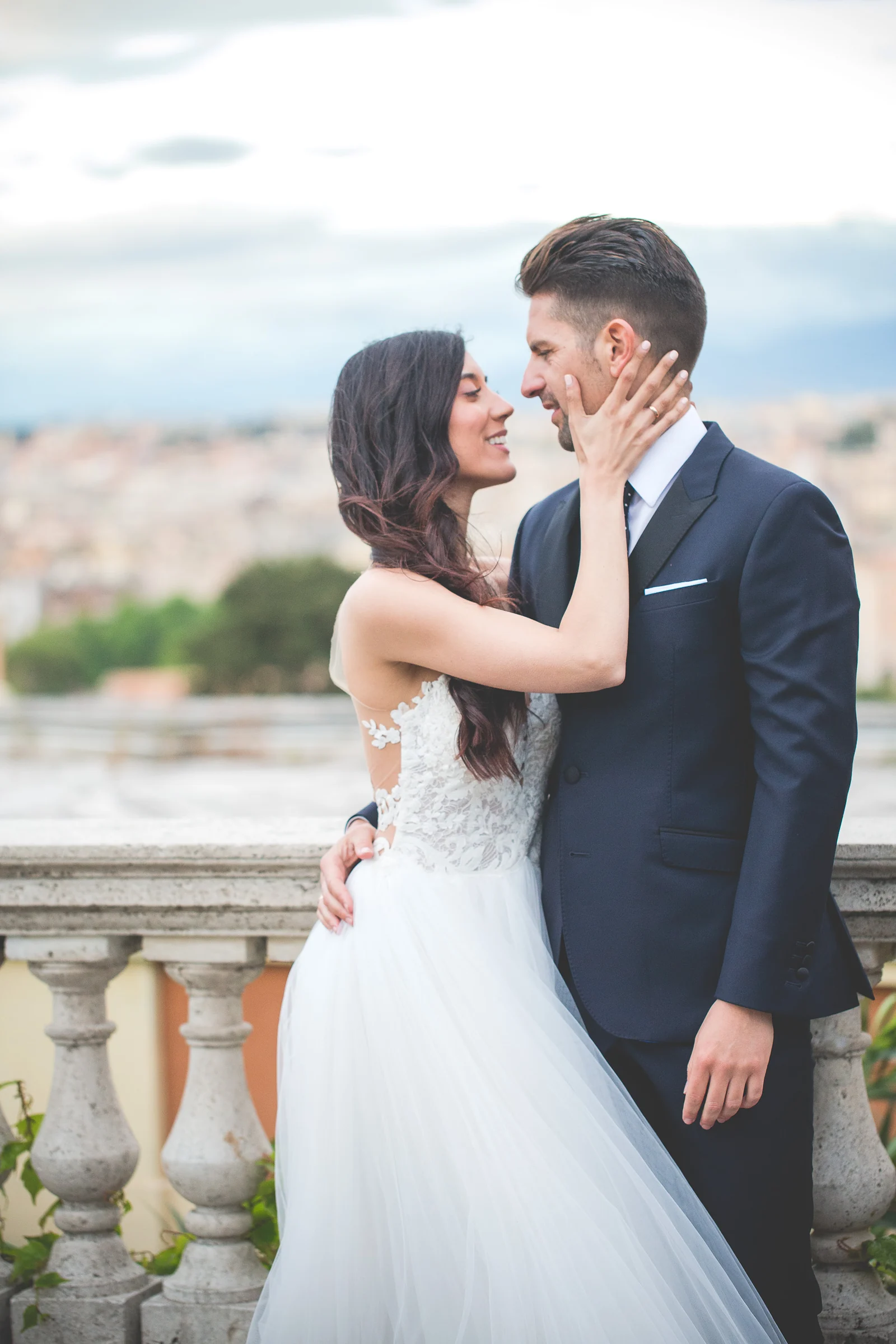 Retrato vertical de los novios mirándose en una terraza monumental durante una sesión postboda en Miradores y centro histórico de Roma.