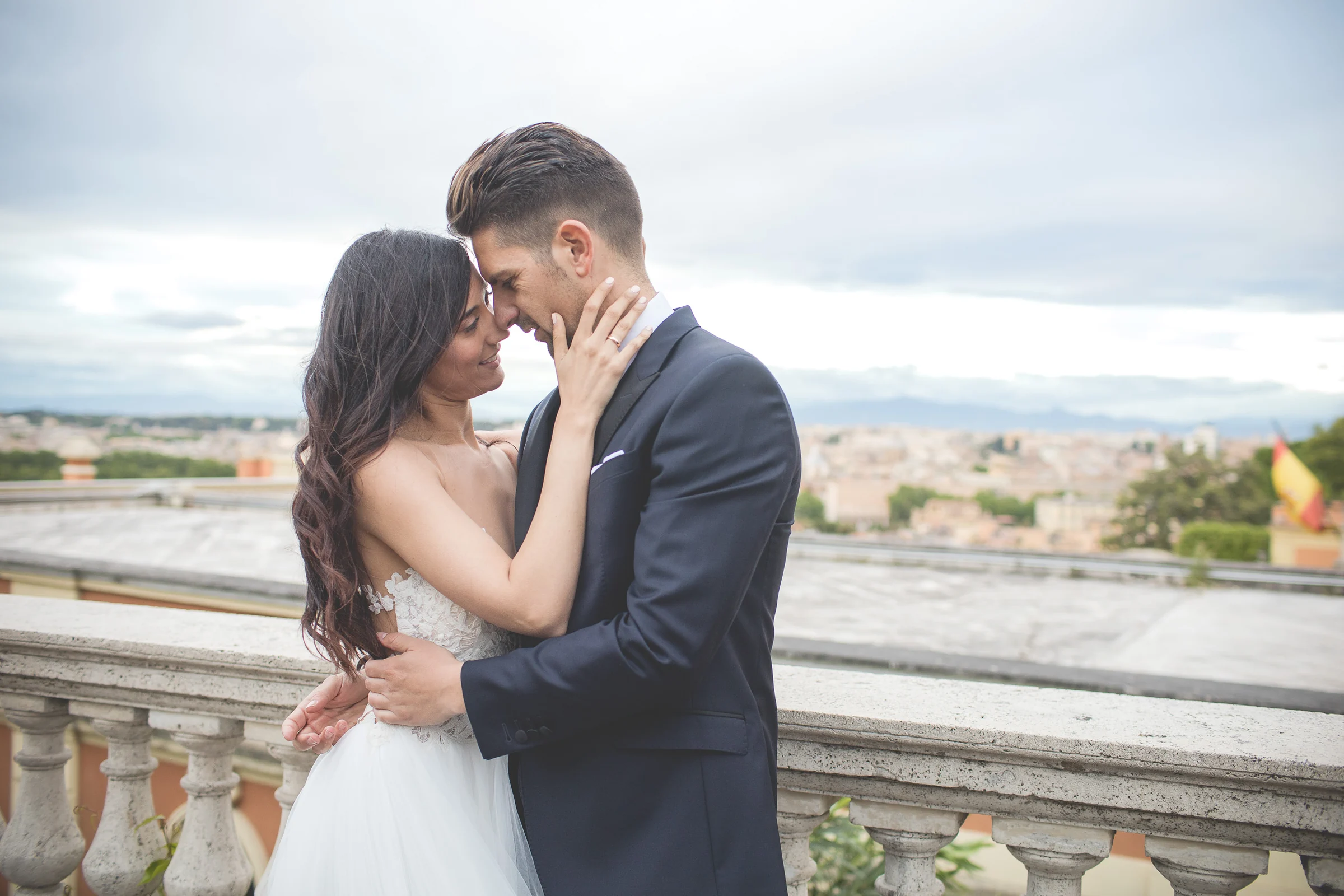 Primer plano de la pareja acariciándose con una vista elevada de Roma durante una sesión postboda en Terraza panorámica de Roma.