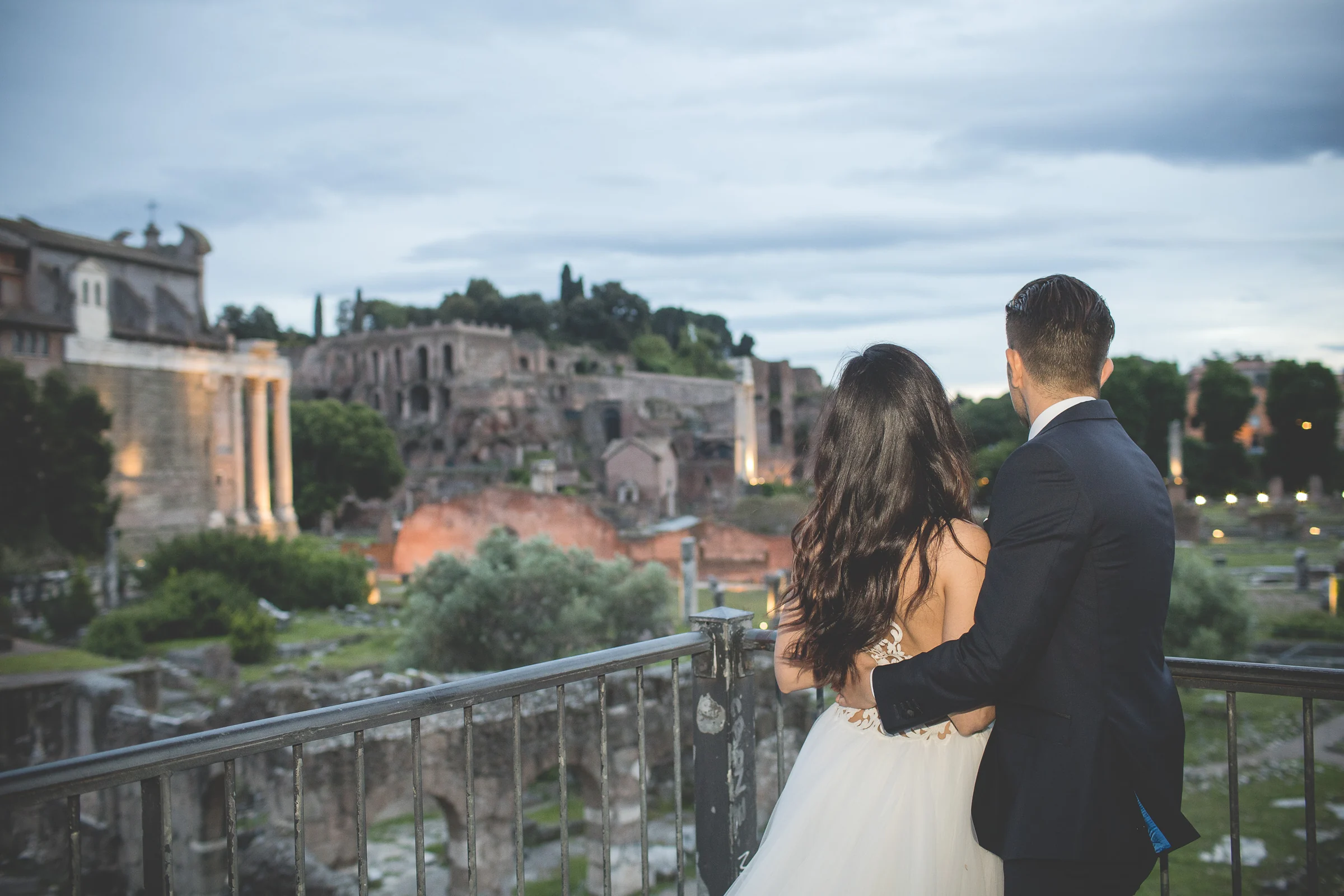 La pareja contempla el Foro Romano desde una terraza al atardecer durante una sesión postboda en Foro Romano.