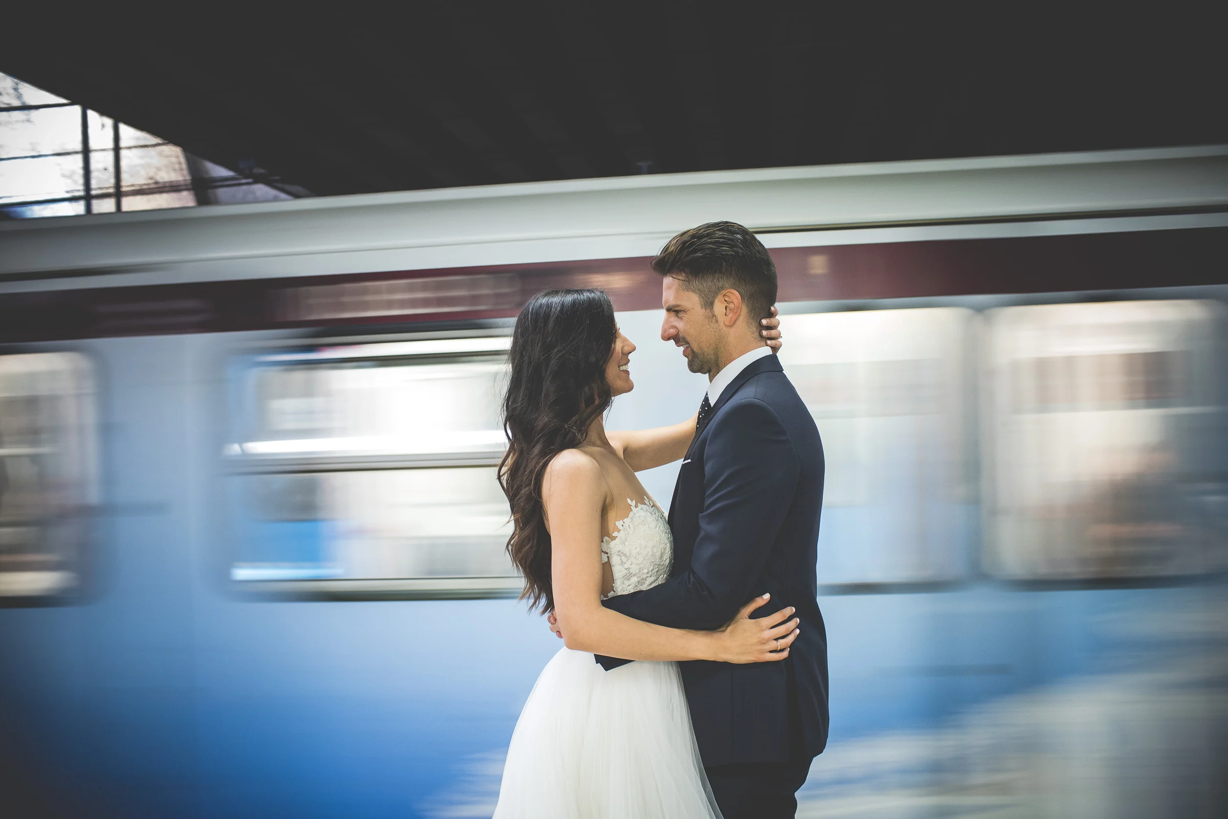 La pareja se abraza en un andén mientras un tren de metro pasa en movimiento durante una sesión postboda en Metro de Roma.