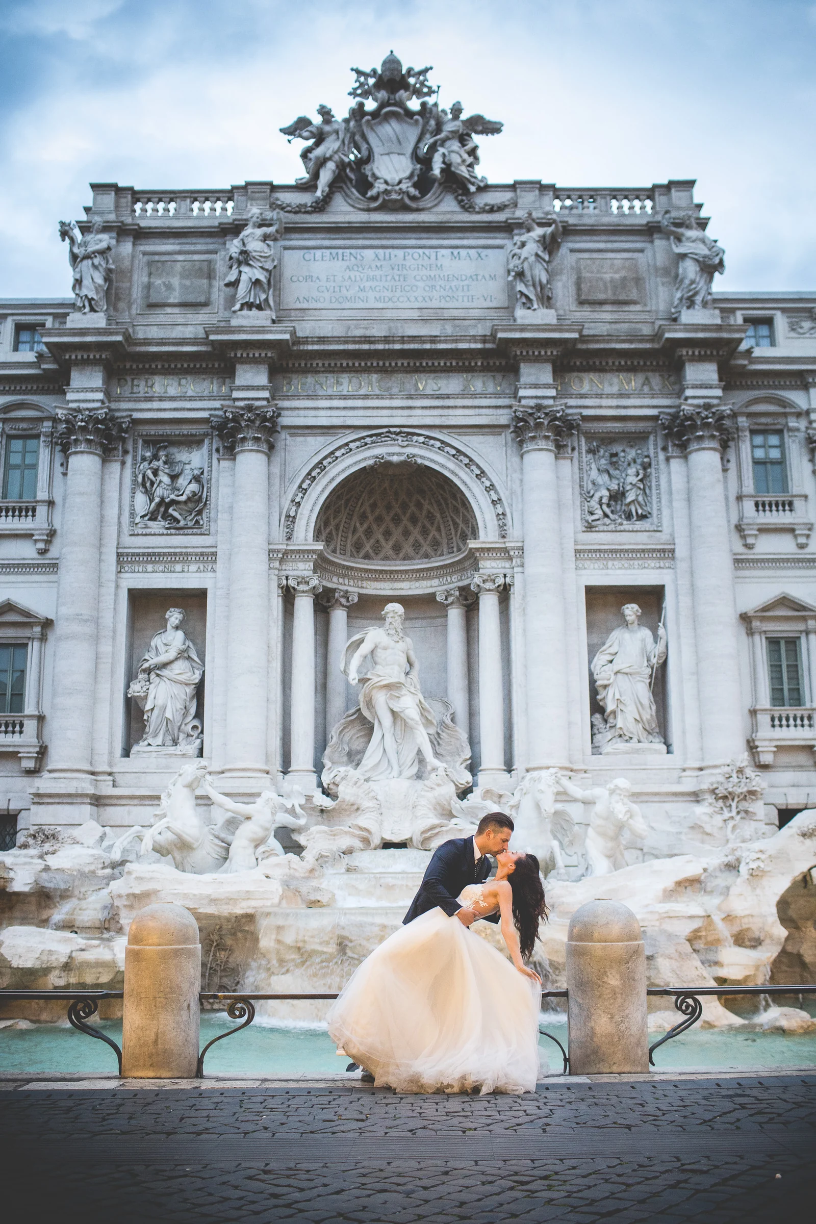 Los novios posan frente a la Fontana di Trevi en una composición monumental durante una sesión postboda en Fontana di Trevi.