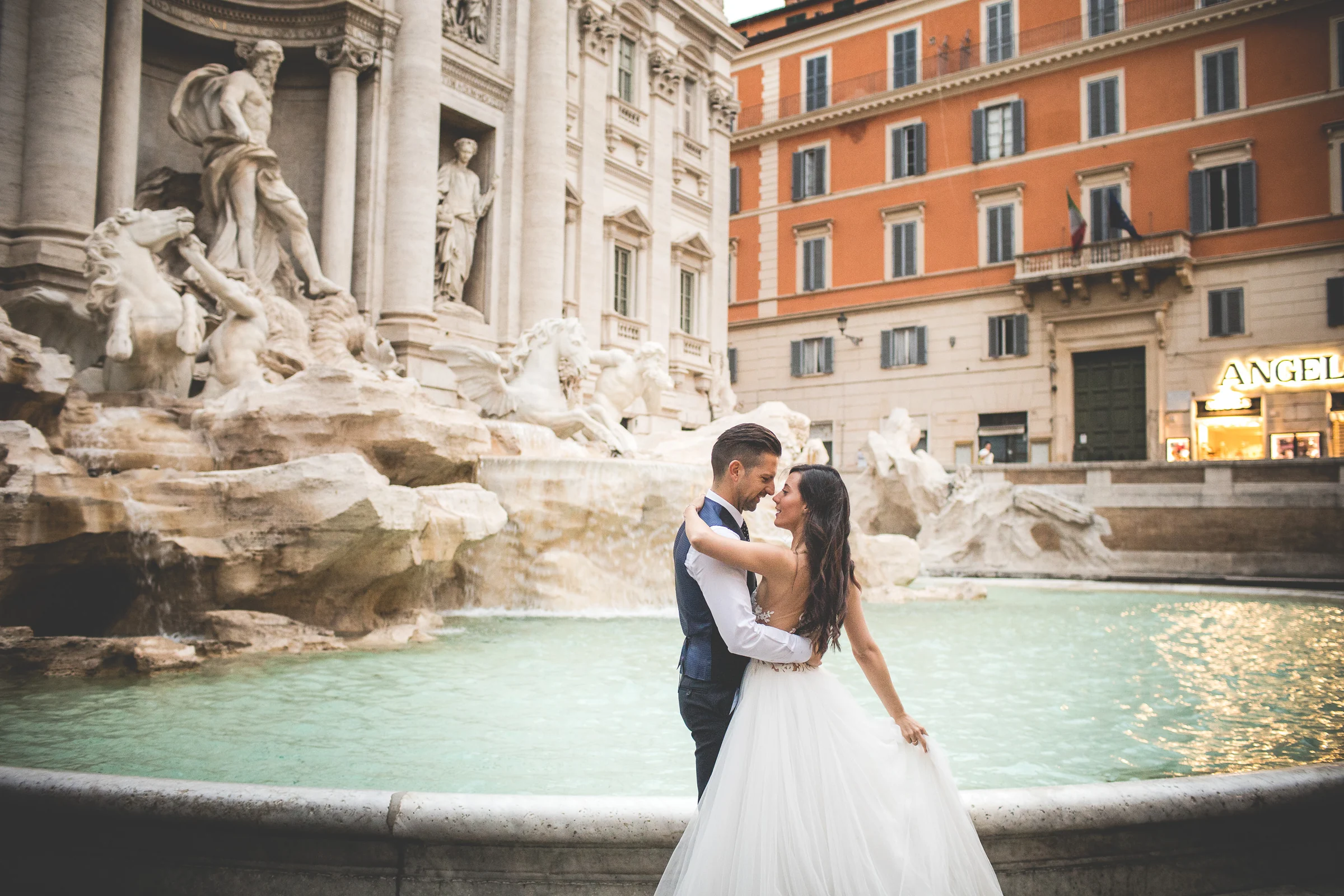 La pareja se abraza junto al borde de la Fontana di Trevi durante una sesión postboda en Fontana di Trevi.