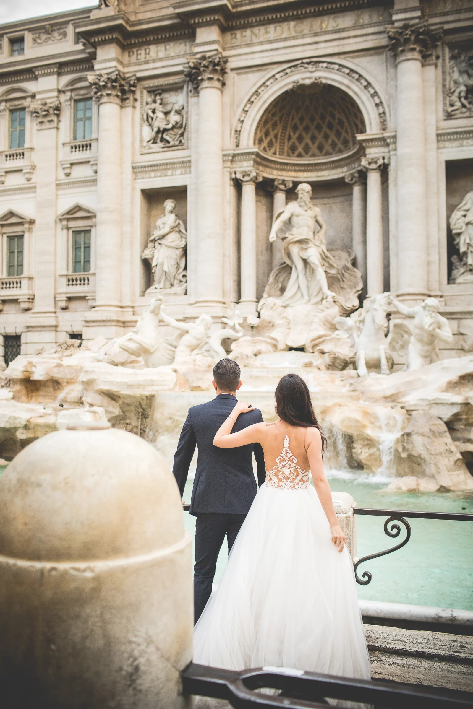 La pareja contempla de espaldas la Fontana di Trevi durante una sesión postboda en Fontana di Trevi.