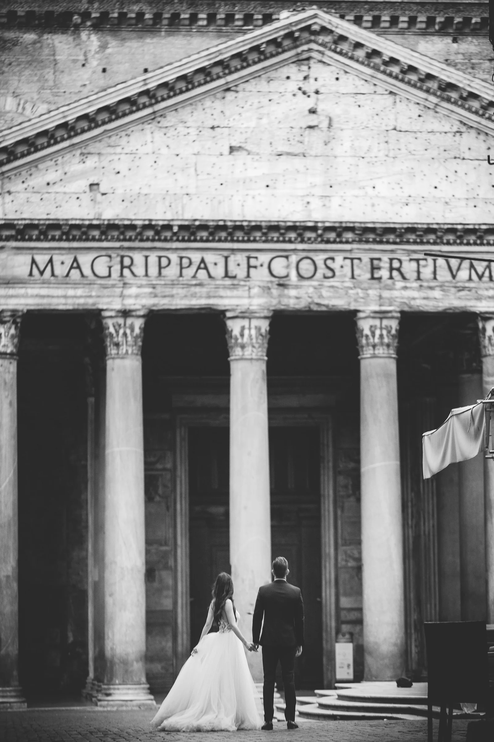 Retrato en blanco y negro de la pareja frente a las columnas del Panteón durante una sesión postboda en Panteón de Roma.