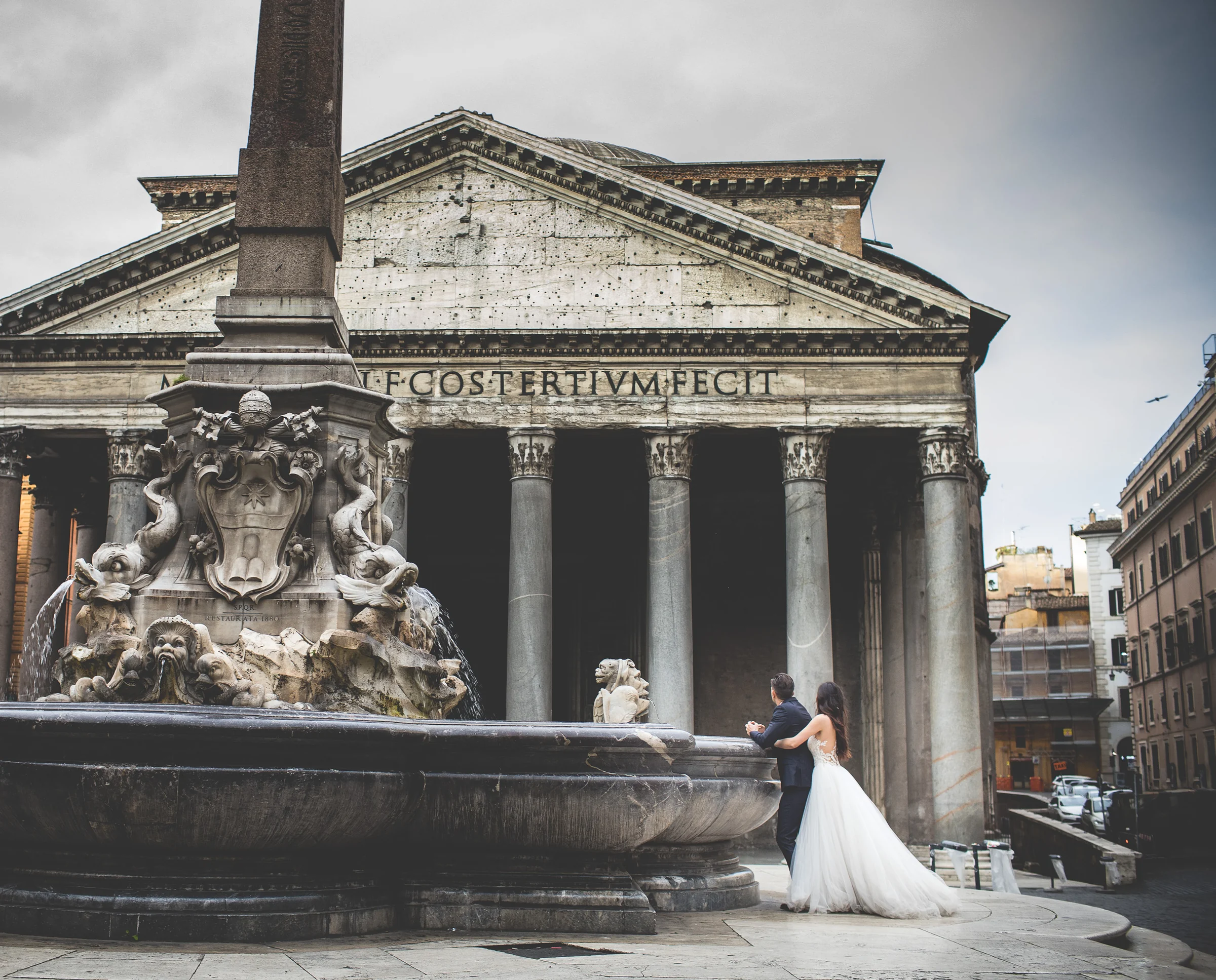 Vista amplia del Panteón con los novios junto a la fuente de Piazza della Rotonda durante una sesión postboda en Panteón de Roma.