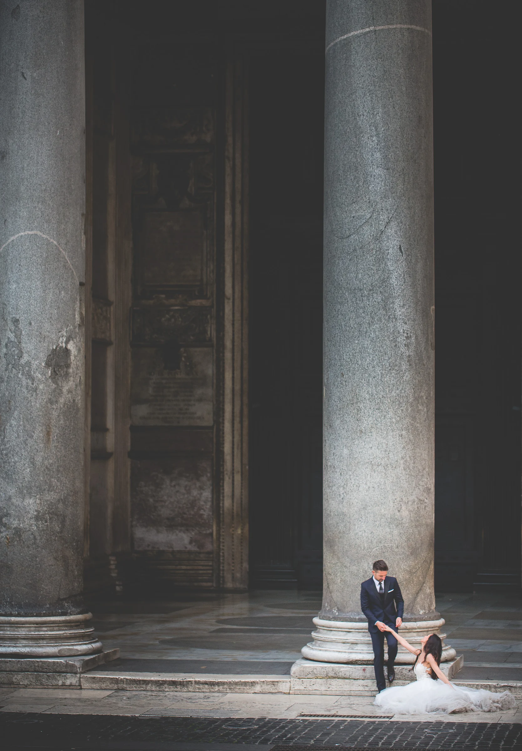 Los novios sentados a los pies de una gran columna del Panteón durante una sesión postboda en Panteón de Roma.